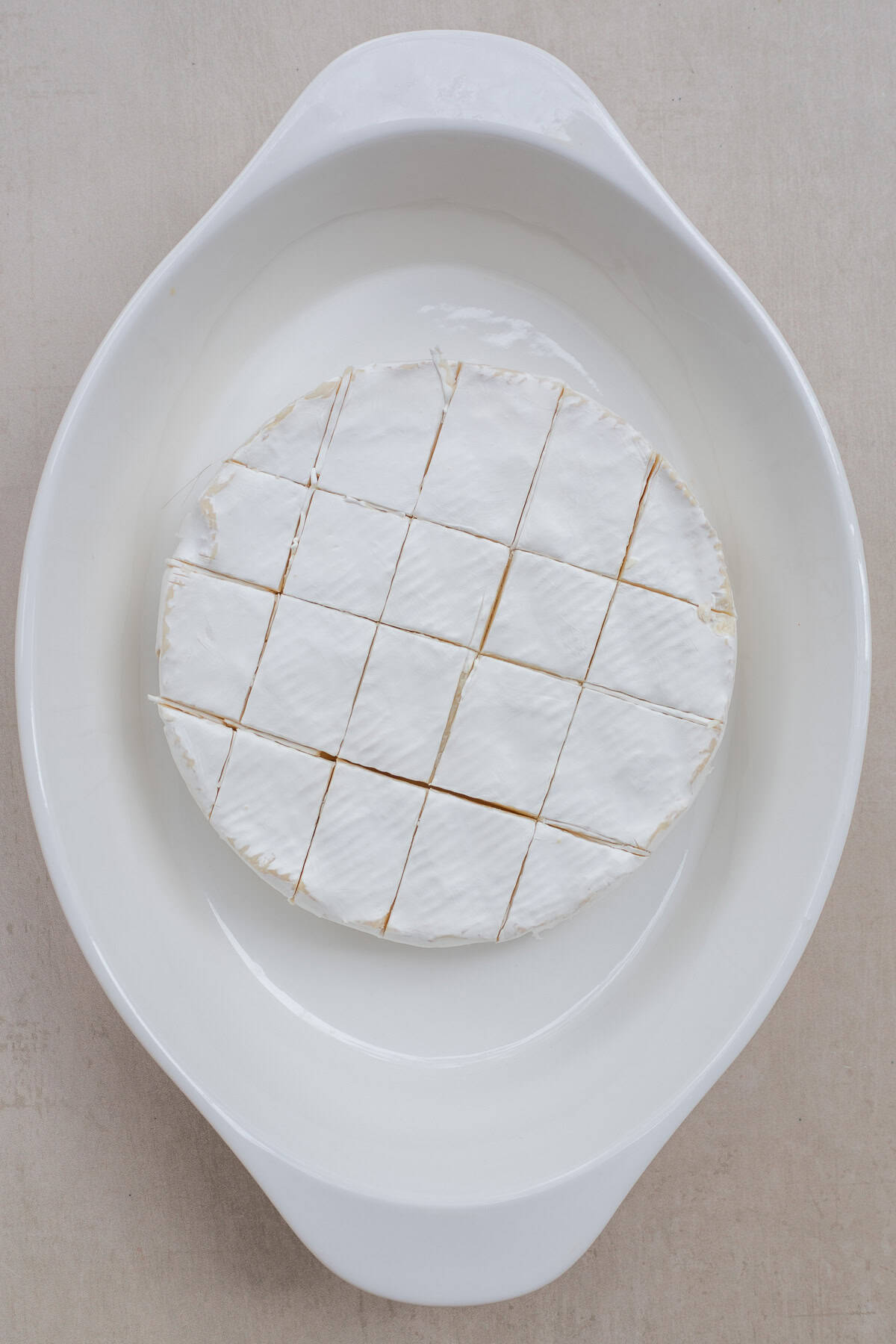 A block of brie cheese makes the perfect appetizer recipe. A casserole dish with the sliced brie cheese.