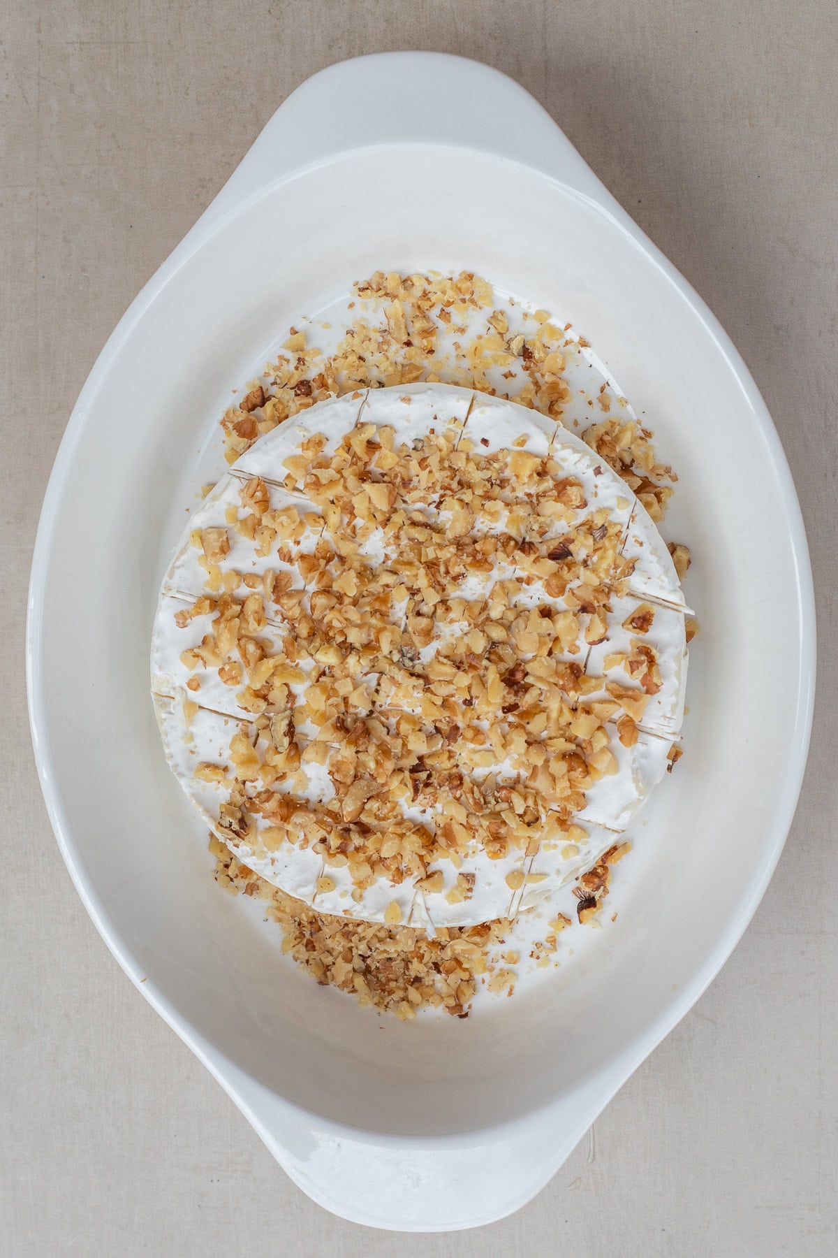 This quick and easy baked brie recipe makes the perfect appetizer recipe. A casserole dish with the brie cheese, topped with walnuts.