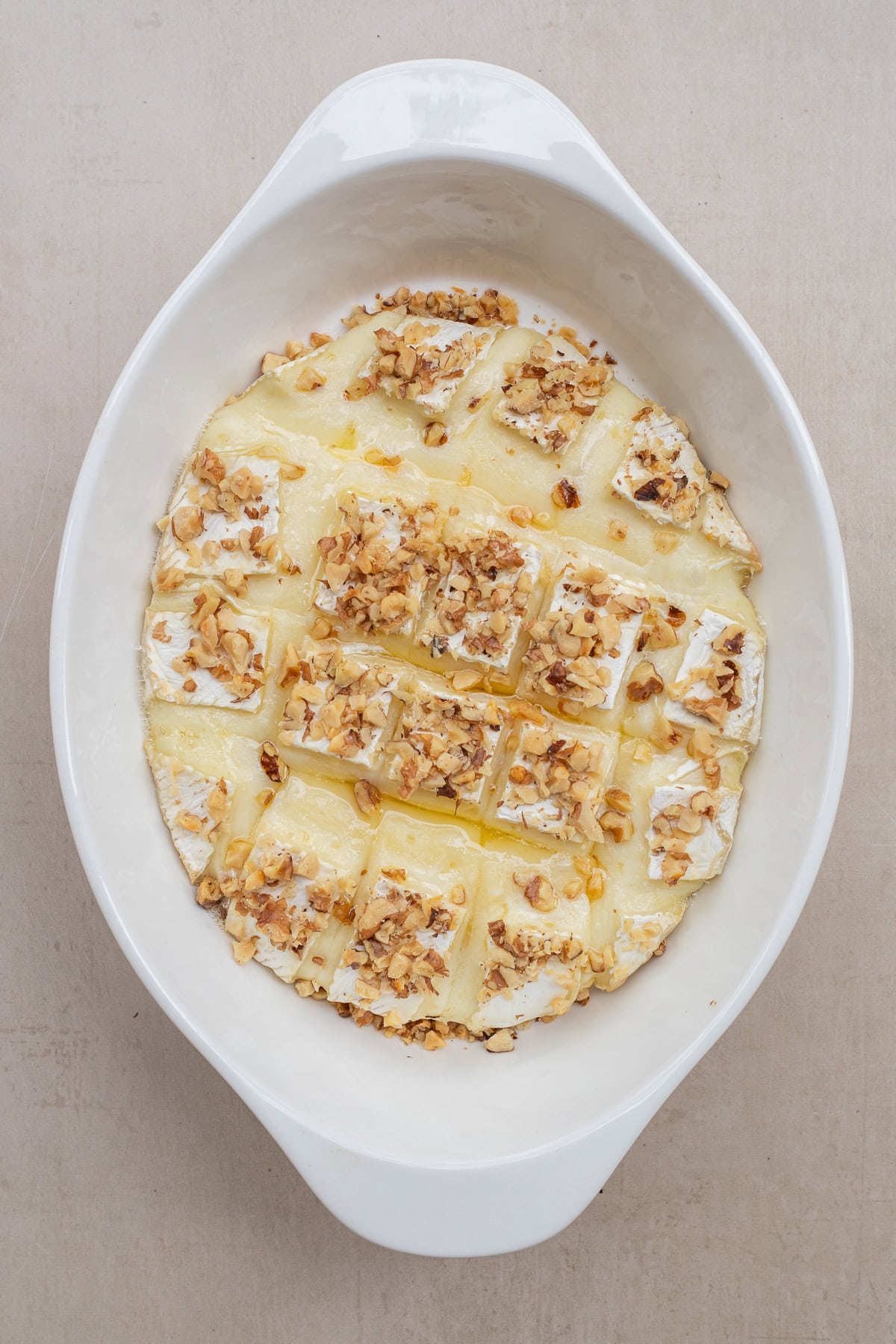 A baked brie appetizer recipe makes the perfect dish to serve for a crowd. The baked brie in a casserole dish.