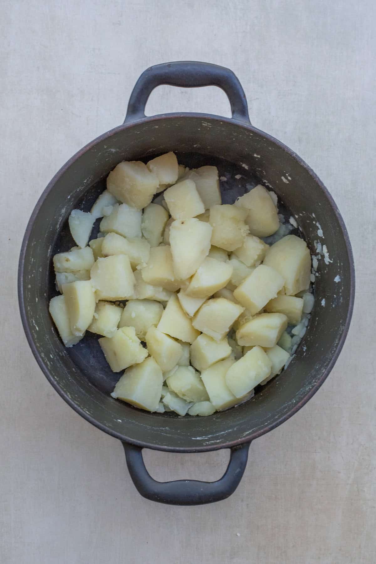 Homemade heavy cream mashed potatoes make a rich and luxurious side dish. A pot of boiled potatoes.