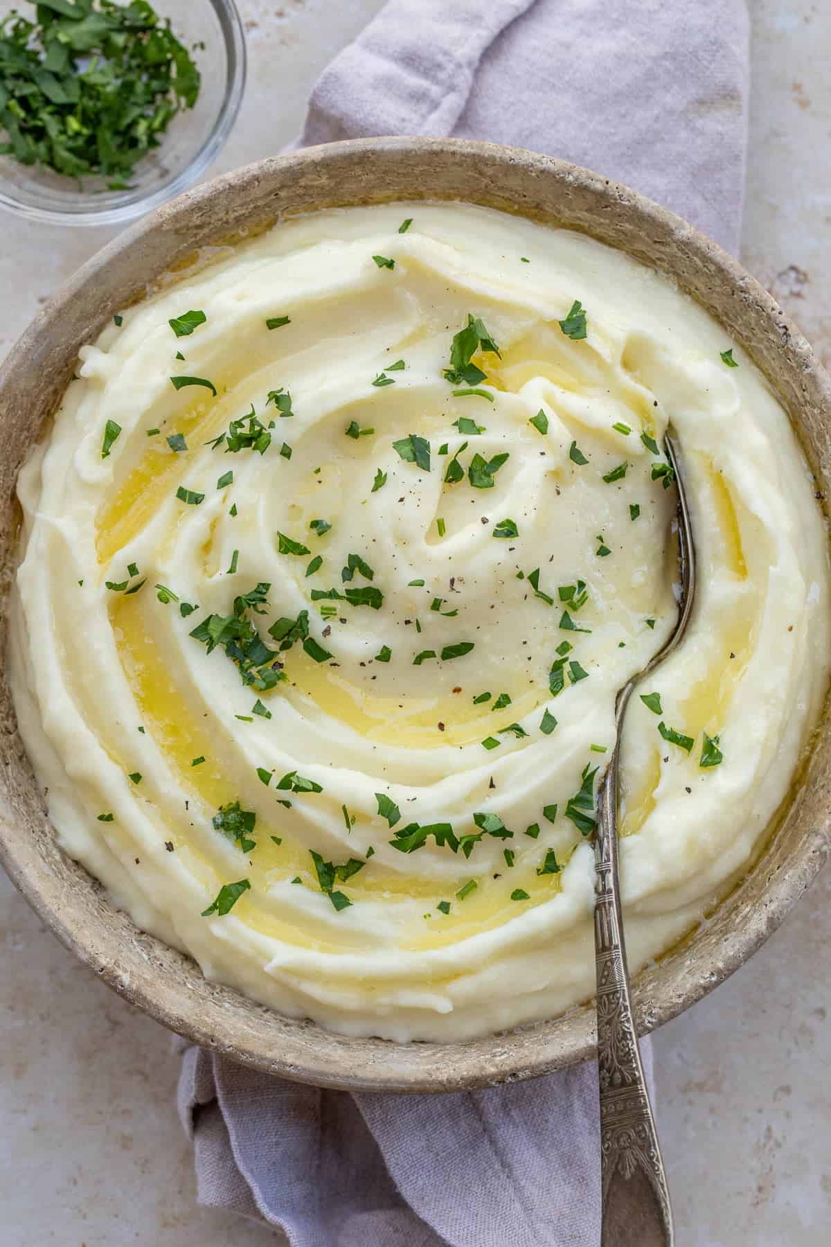Homemade mashed potatoes with cream turn out extra fluffy and rich. A bowl of creamy mashed potatoes with a spoon in it.