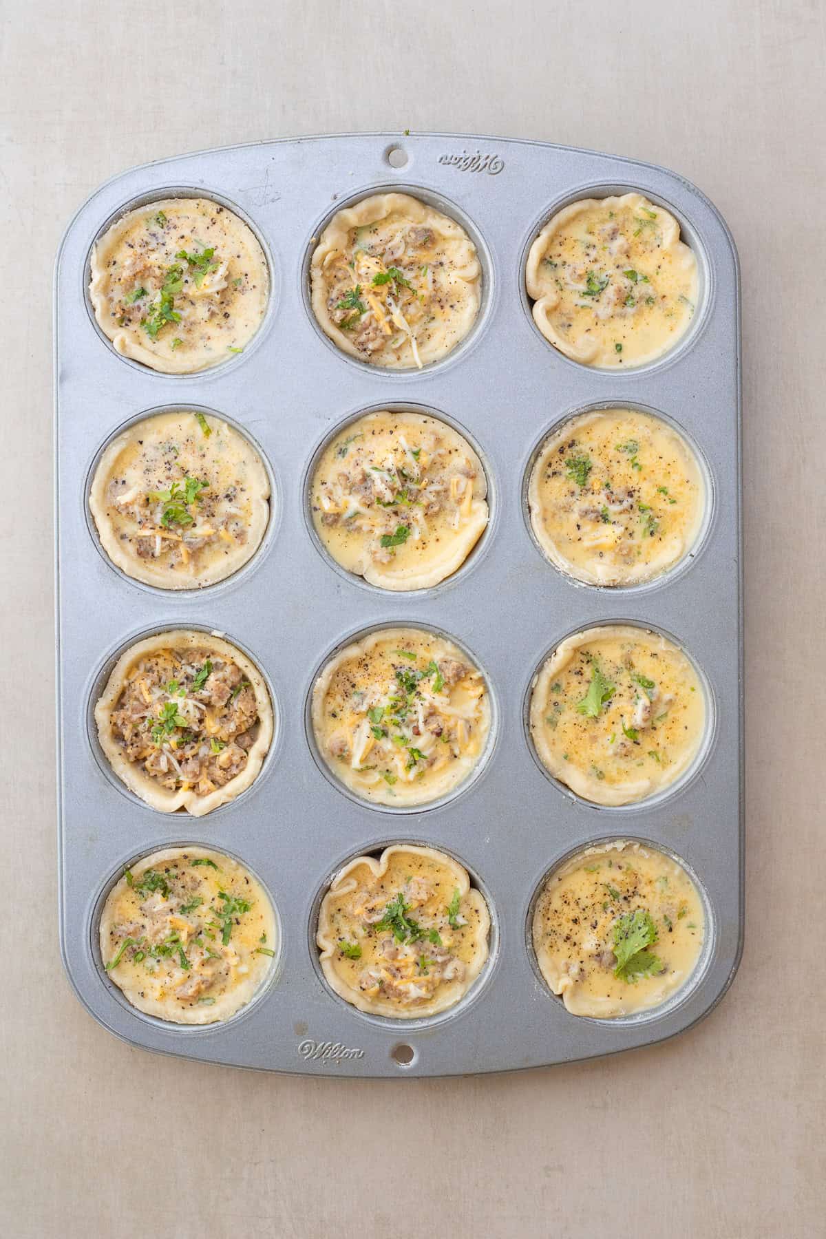 The perfect mini quiche recipe that makes for the perfect breakfast The muffin tin with the pie crust in the molds, filled with the egg mixture.