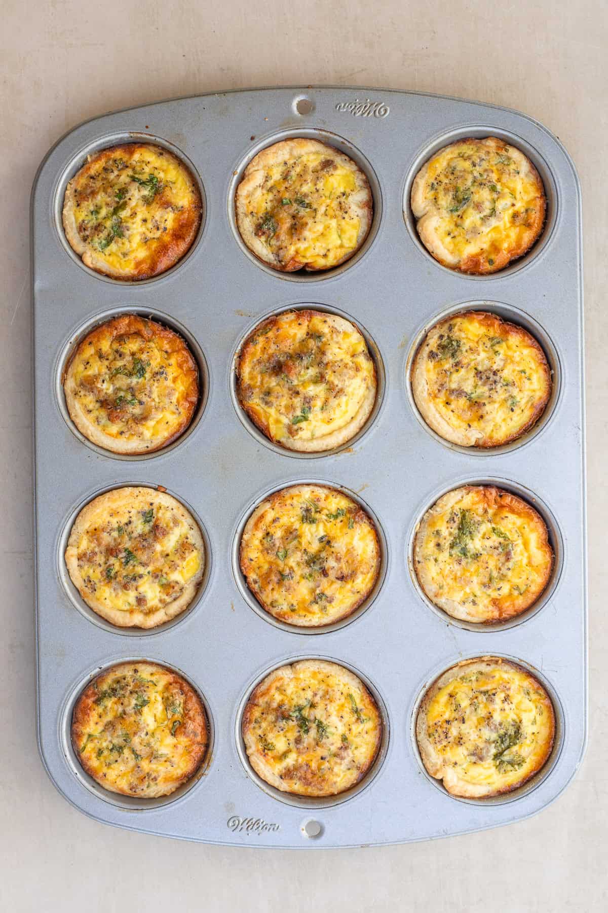 A classic mini quiche recipe makes an impressive breakfast from scratch. A muffin pan with the baked mini quiches.