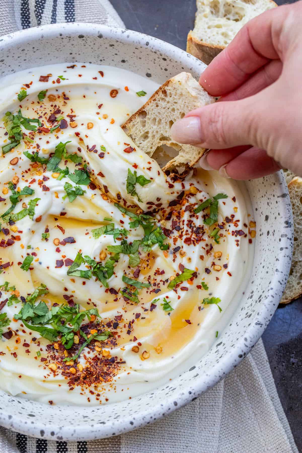 Best Whipped Ricotta Recipe with Honey A bowl with the creamy ricotta spread topped with herbs.