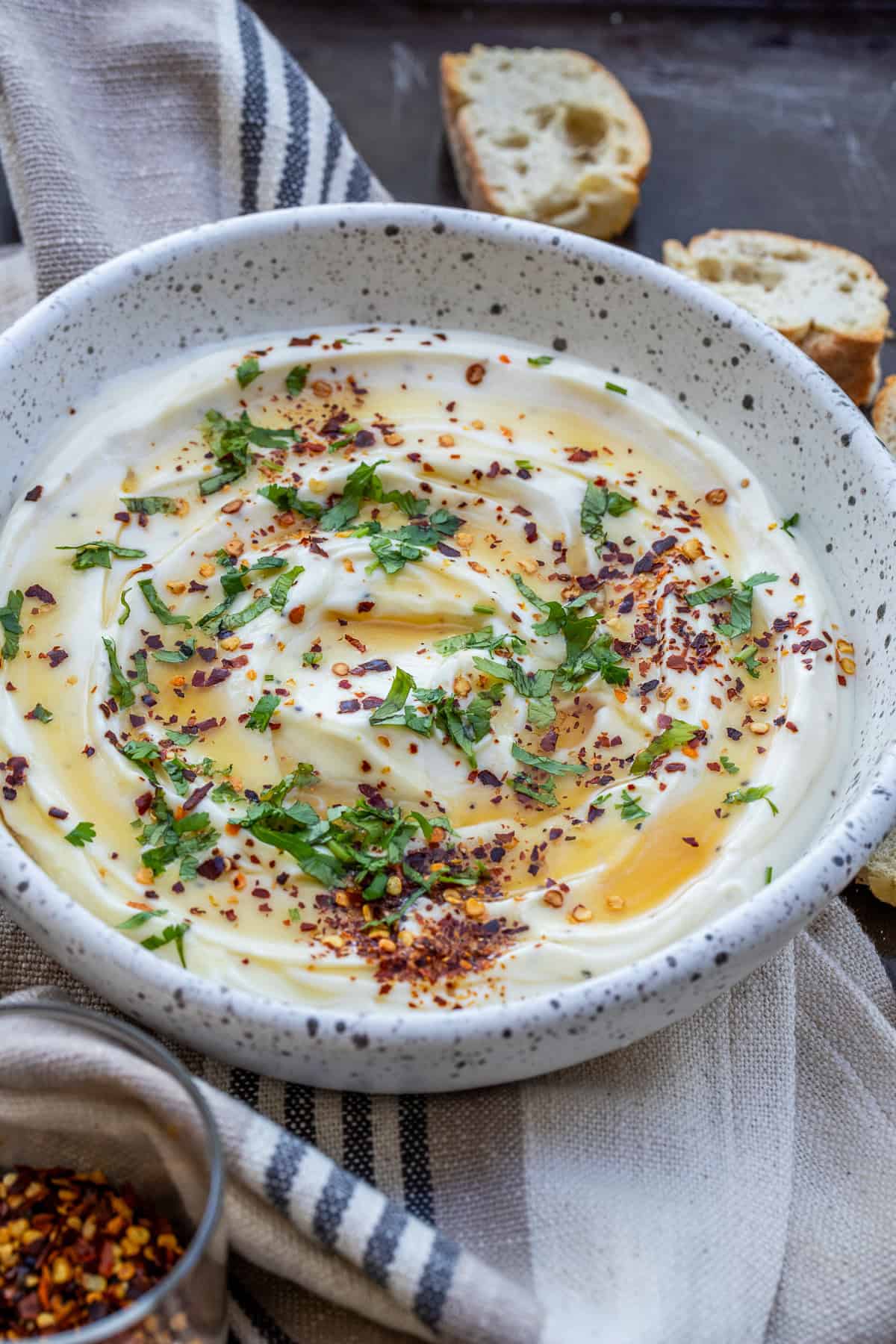 5-Minute Whipped Ricotta Recipe (No Cooking Required) A bowl of whipped ricotta sprinkled with red pepper flakes and drizzled with honey.