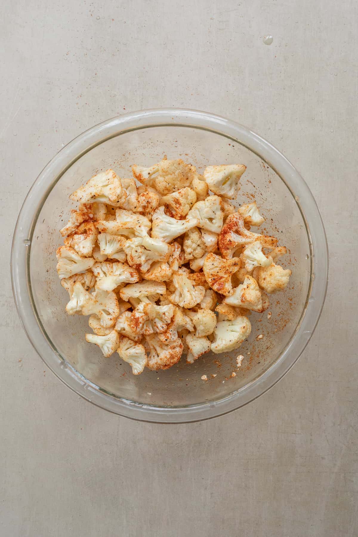 Best Air Fryer Cauliflower (Crispy Outside, Tender Inside) A glass bowl with the seasoned cauliflower florets.
