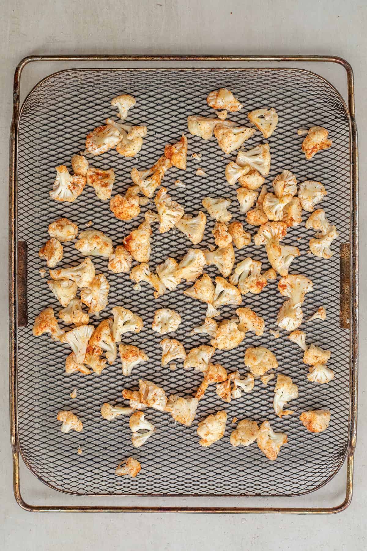 Crispy Air Fryer Cauliflower Recipe Easy An air fryer basket with the cauliflower florets seasoned.