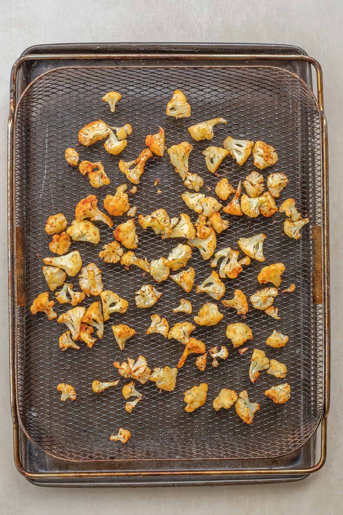 Air Fryer Cauliflower Florets Recipe An air fryer basket with the toasted cauliflower florets.