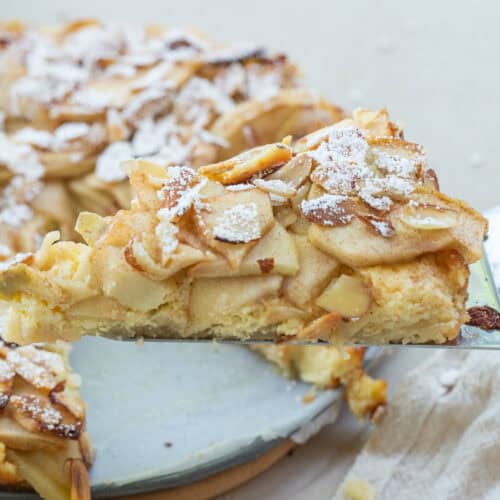A slice of apple torte topped with powdered sugar.