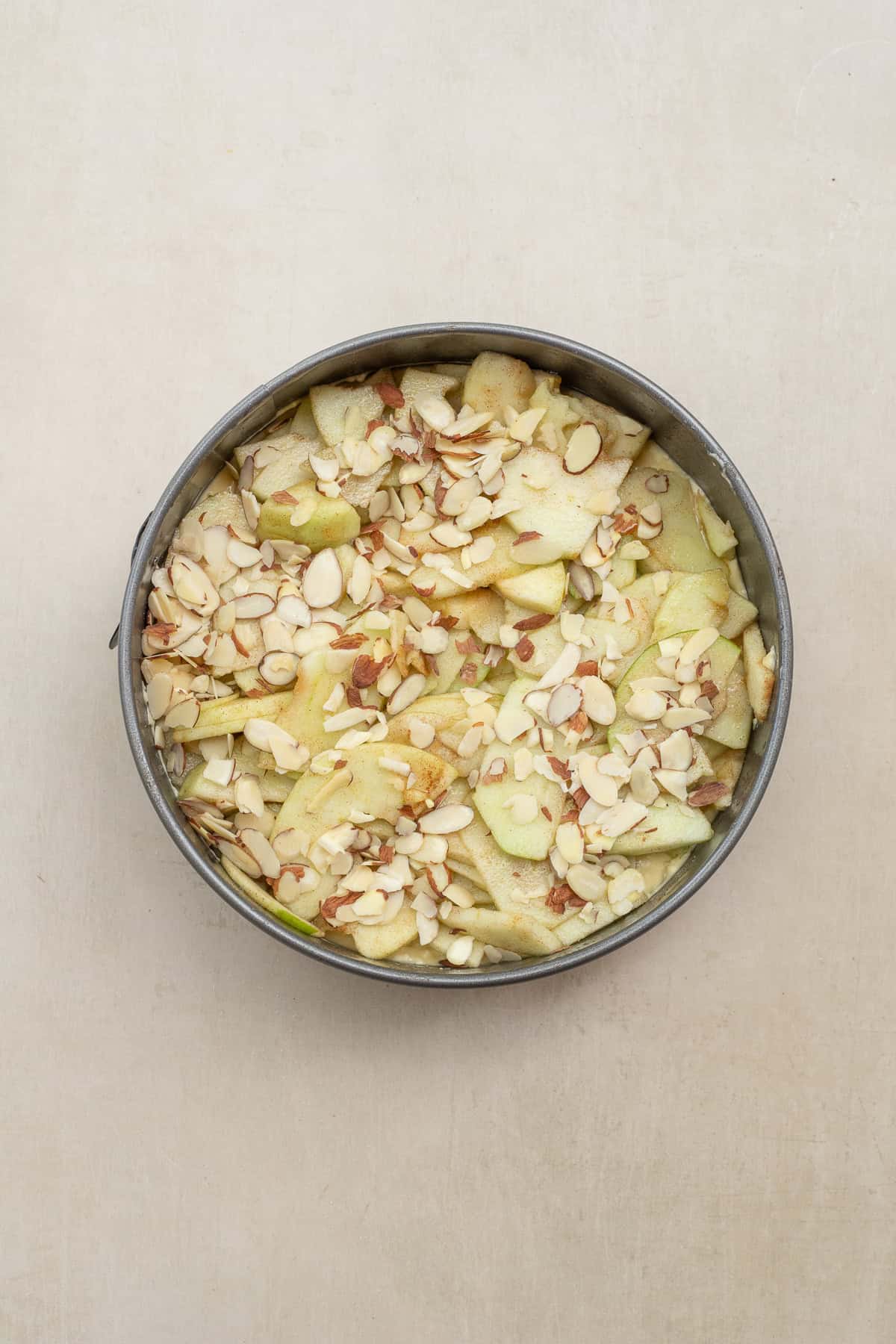 A creamy Bavarian apple torte topped with cinnamon apples and crunchy almonds makes the perfect dessert for holidays, brunches, or family gatherings. This classic apple torte recipe is simple yet impressive. An apple torte assembled in a springform pan.