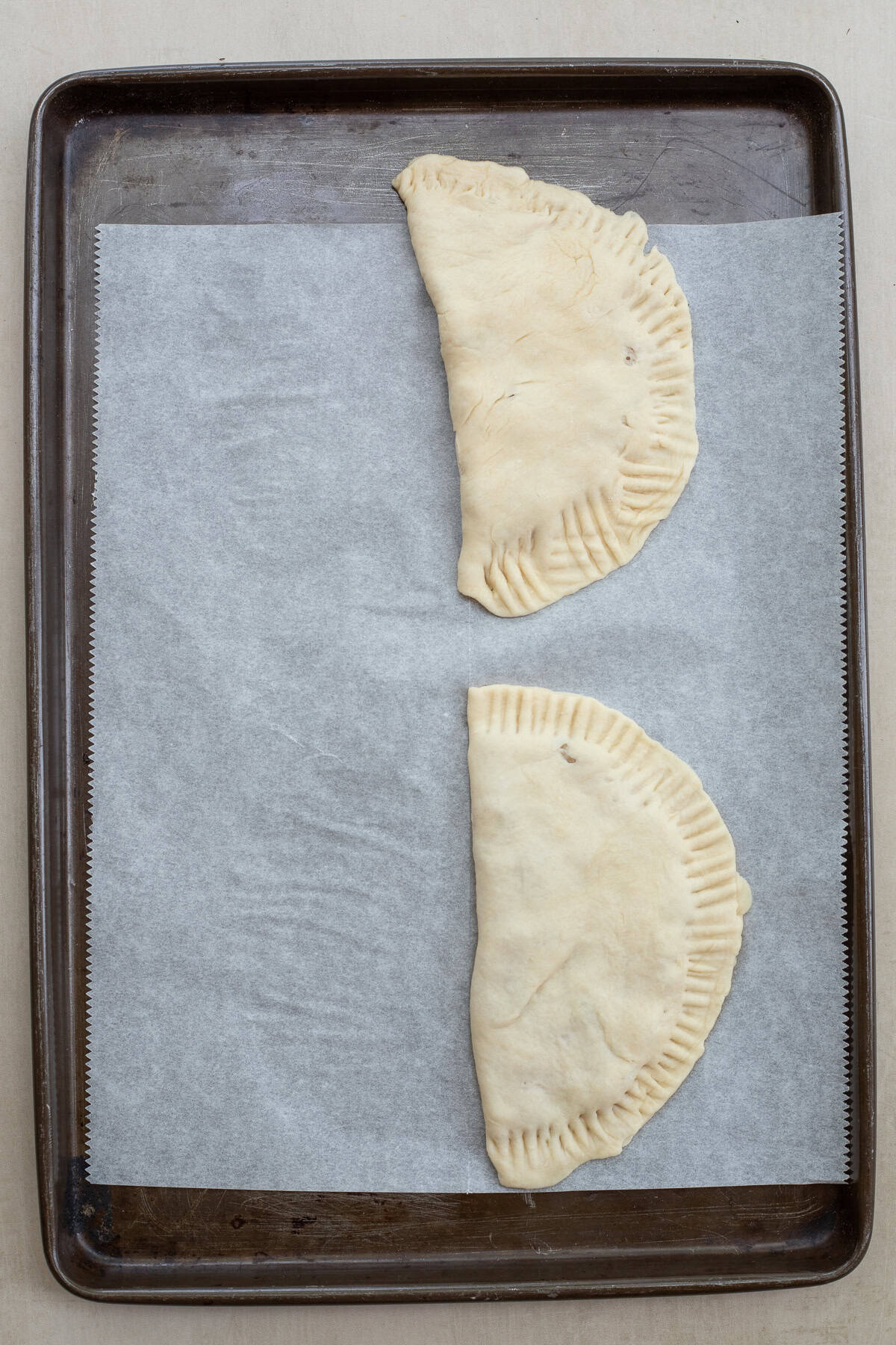 What makes these chicken chebureki the best is the homemade dough and chicken filling. The chebureki folded over, sealed, and ready to be fried.