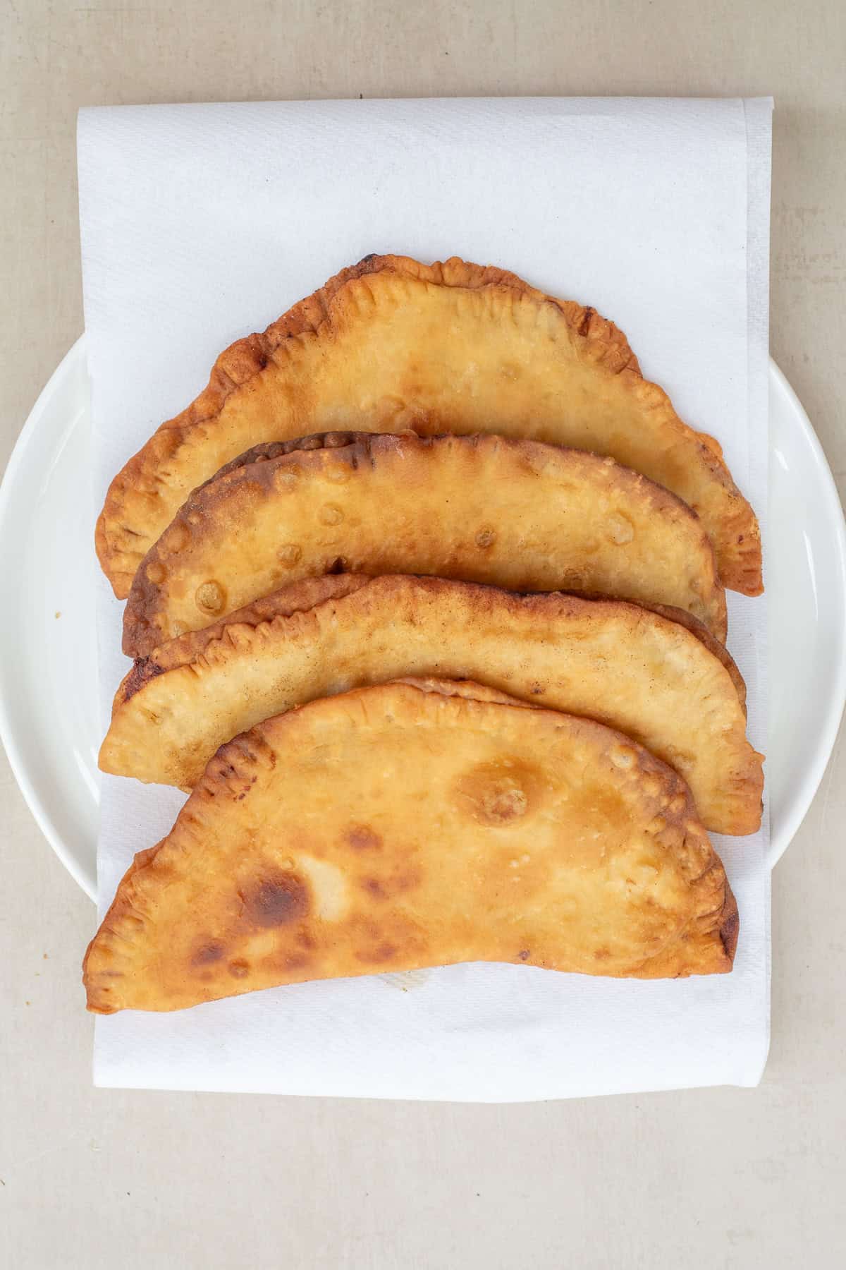 Crispy chicken chebureki are loaded with a juicy chicken filling. The chebureki fried and laid on a paper towel.