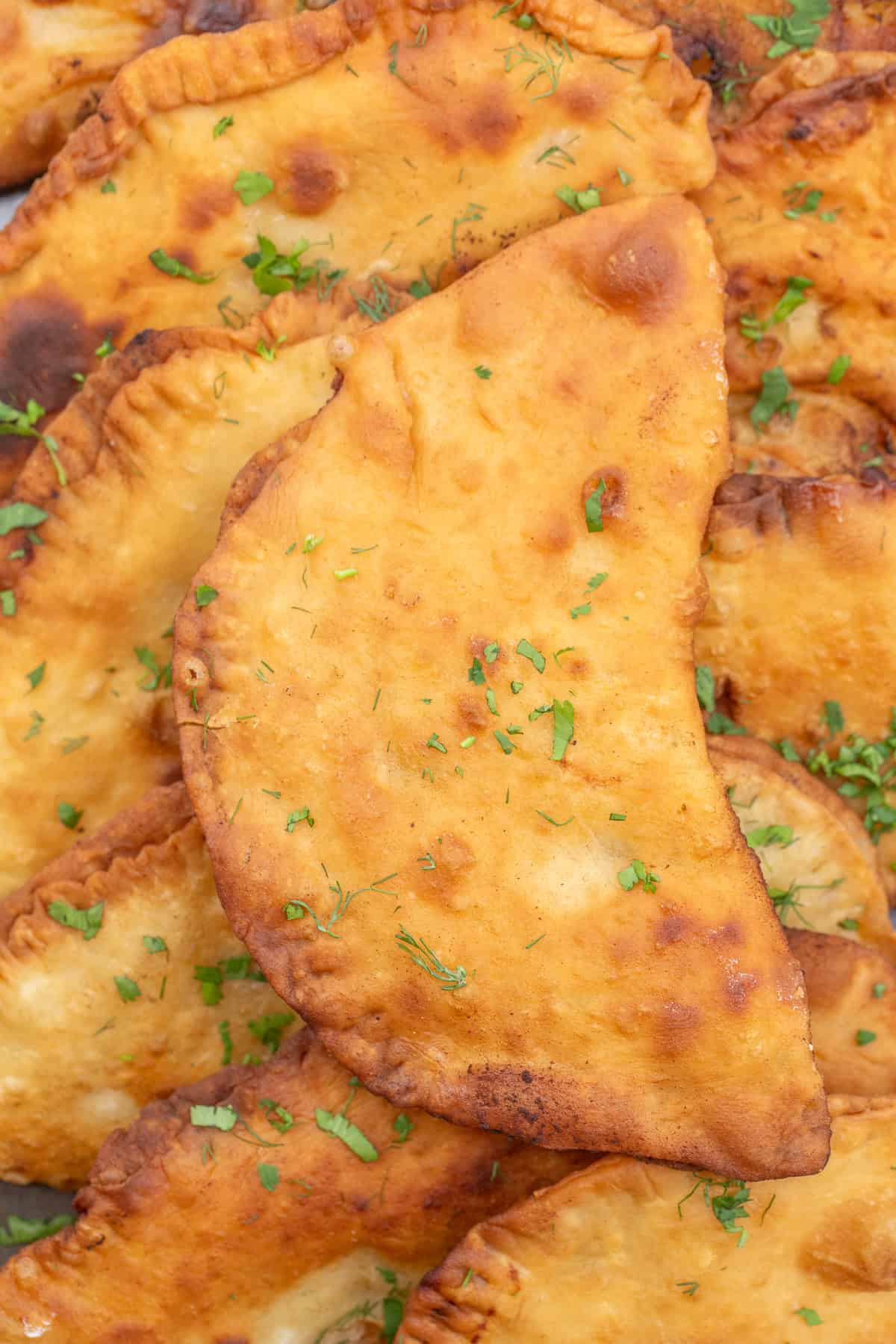 A fan favorite - chicken chebureki made from scratch. Crispy chebureki laid out on top of each other.