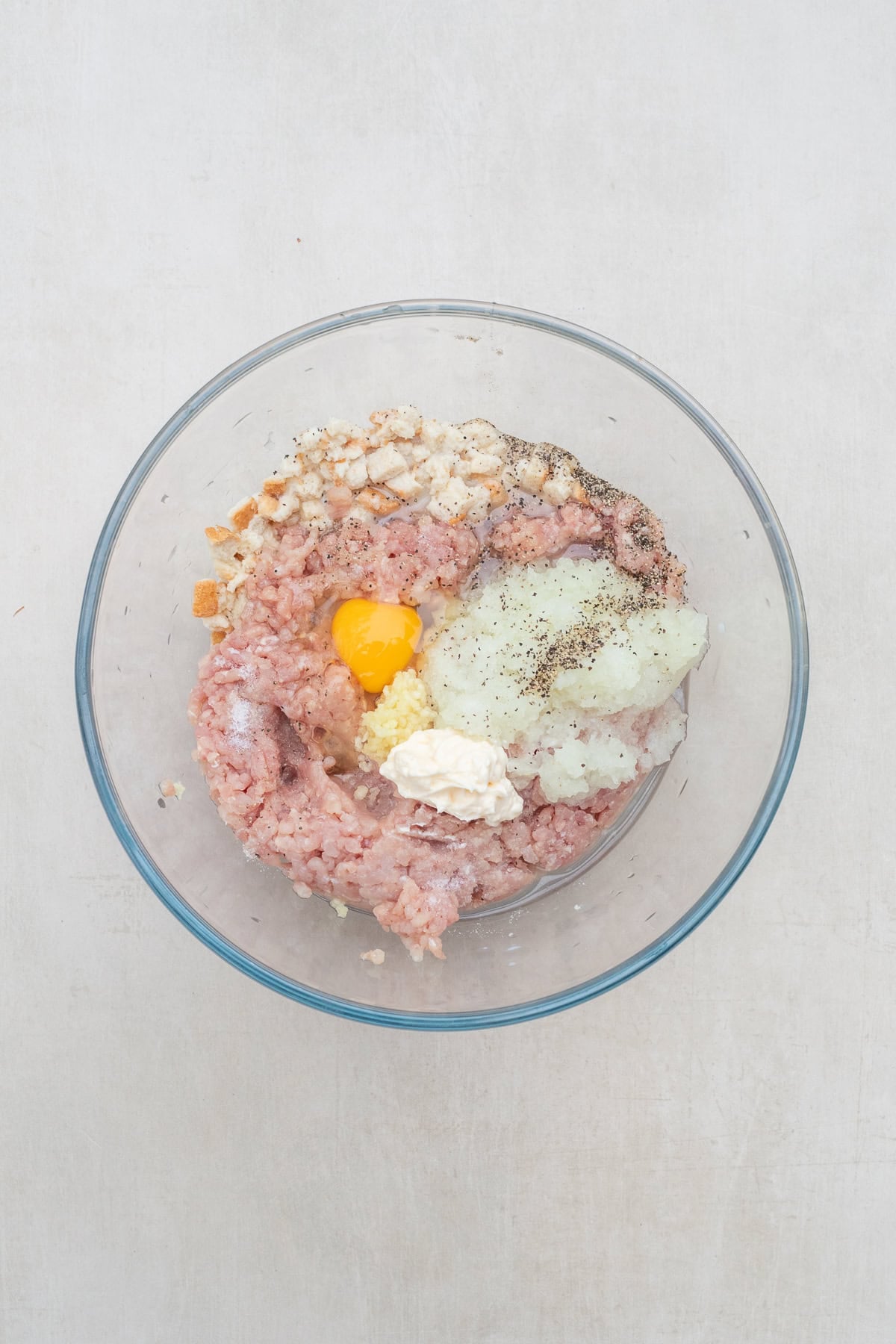 Simple Chicken Patties Recipe with Ground Chicken A glass bowl with the meat patty mixture.