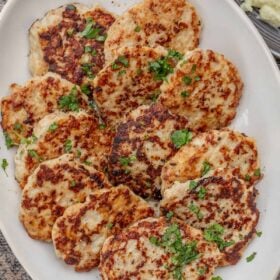 A large serving dish with the arranged chicken patties, garnished with fresh herbs.