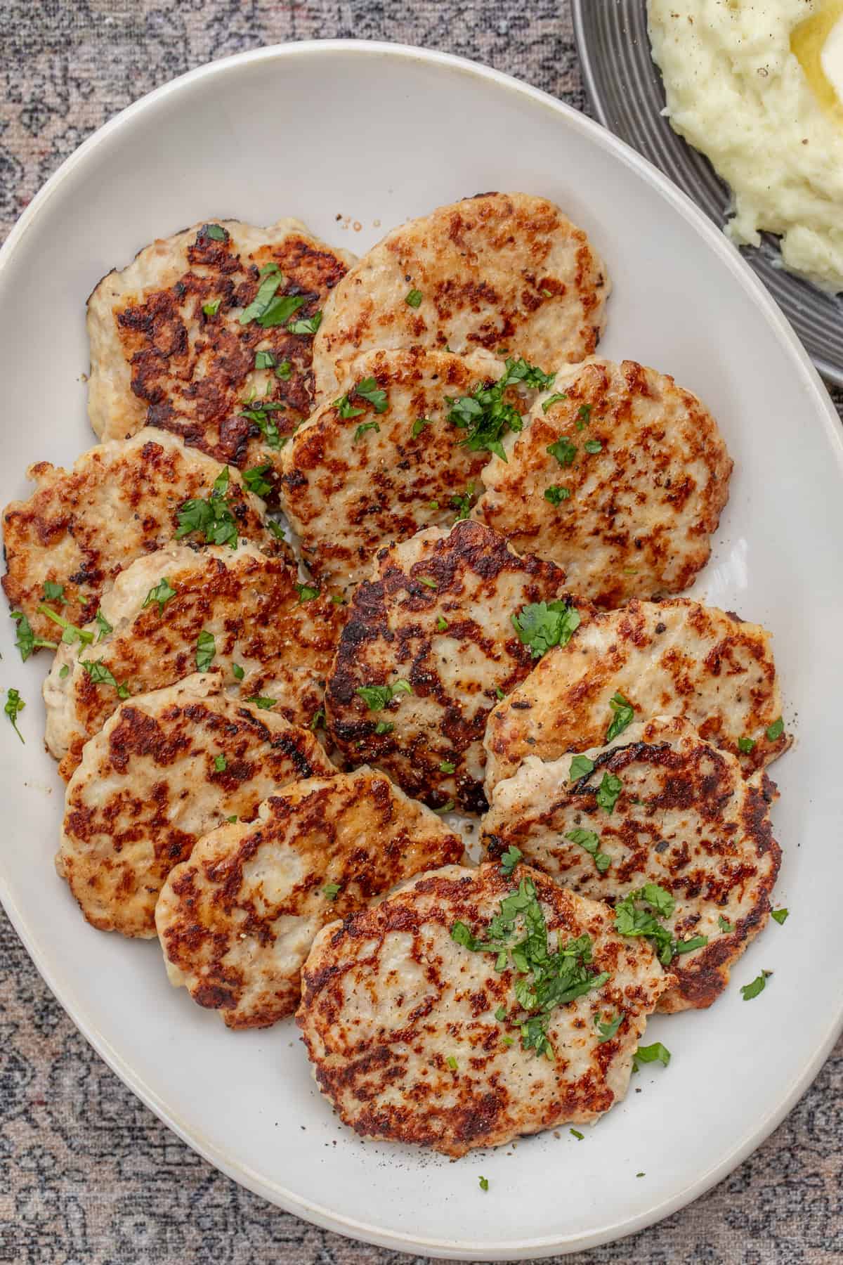 Easy Chicken Patties Recipe (Crispy & Juicy) A large serving dish with the arranged chicken patties, garnished with fresh herbs.
