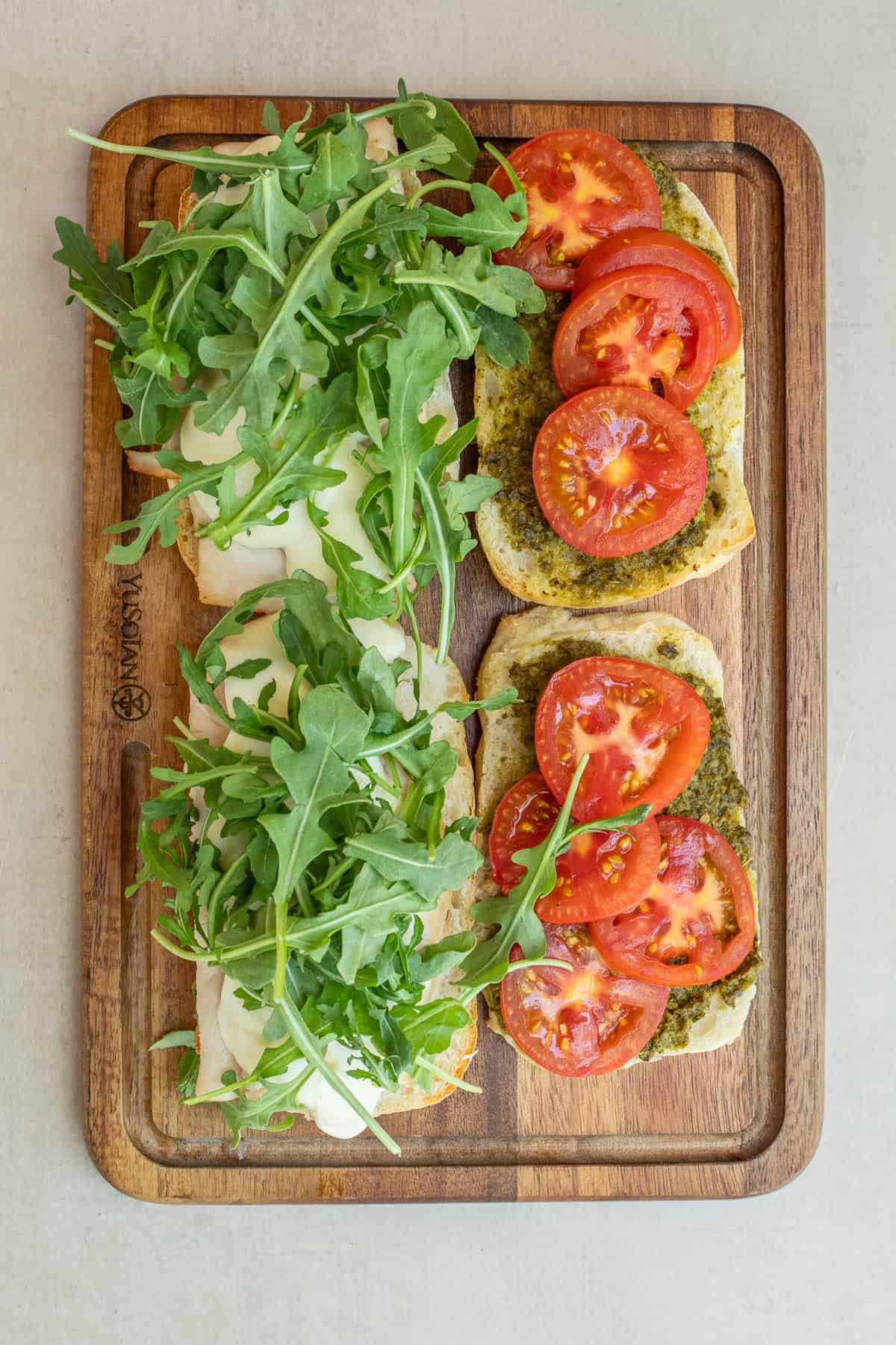 Mozzarella Chicken Pesto Sandwich The arranged pesto chicken sandwiches layered with greens and tomatoes.