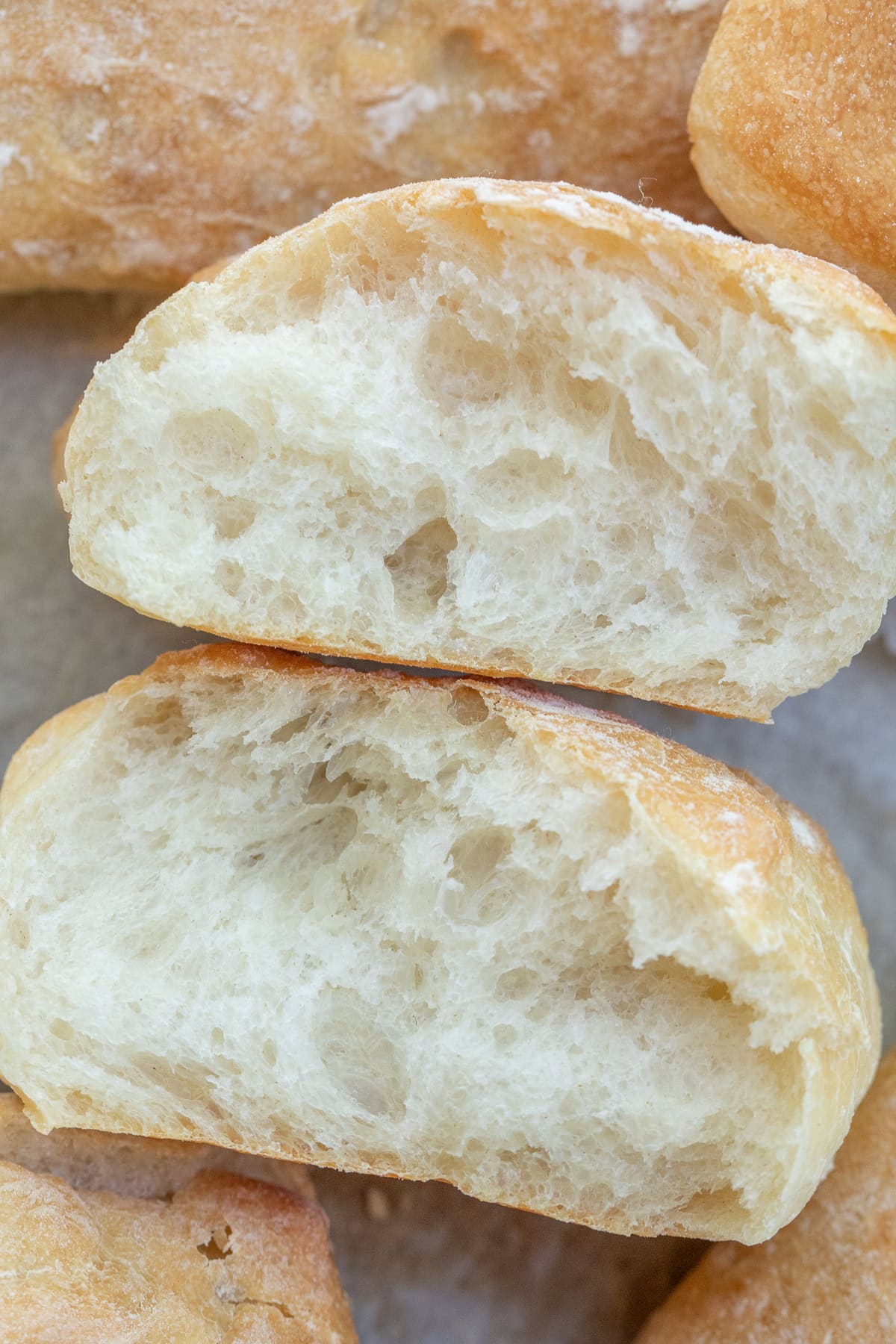 Crispy and Airy Ciabatta Rolls Ciabatta roll sliced in half showing the airy texture.