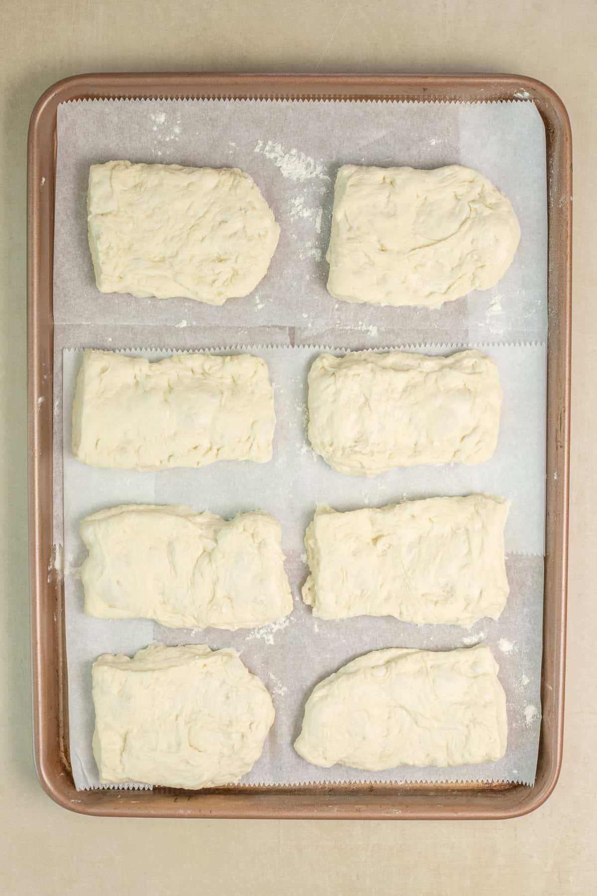 Fluffy Ciabatta Rolls with Crispy Crust The ciabatta loaves arranged on a baking sheet.