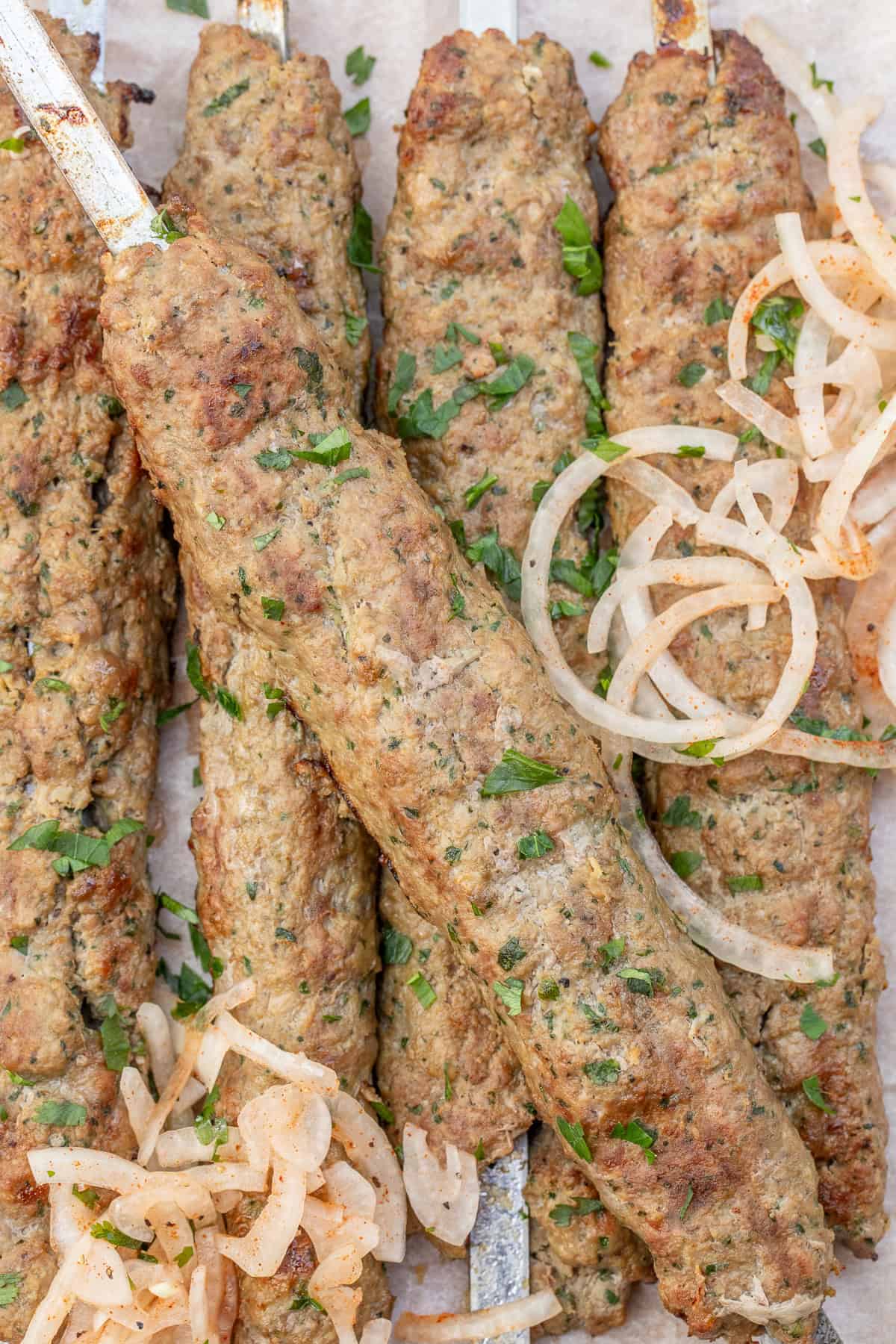 Juicy Ground Lamb Kebabs with Mediterranean Flavors Lamb kebabs topped with fresh herbs and onion salad.