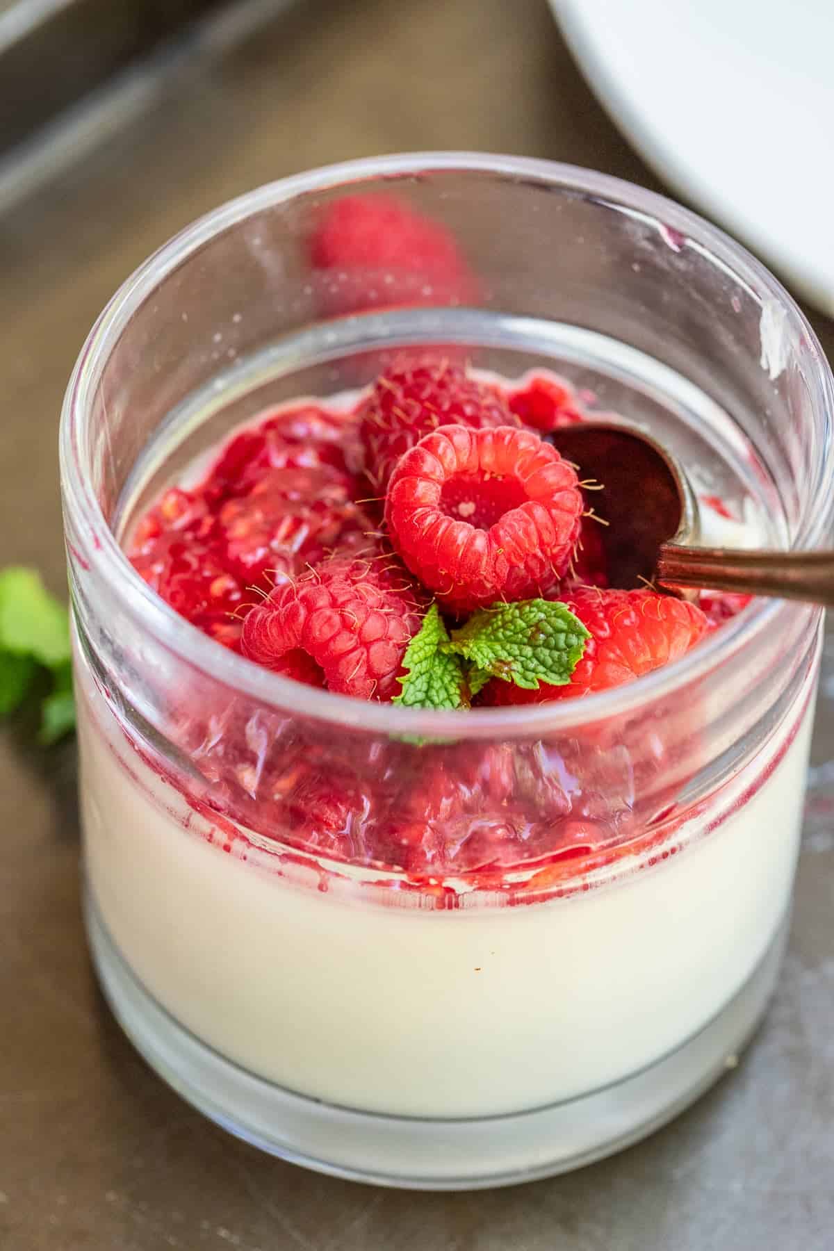 A glass jar with the homemade panna cotta and raspberry topping. 