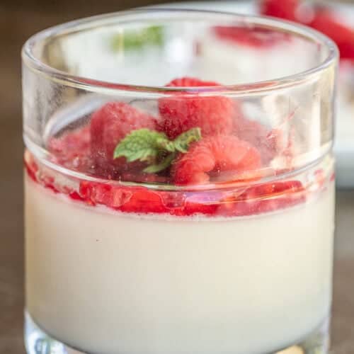 A glass dish with homemade panna cotta topped with raspberry jam.