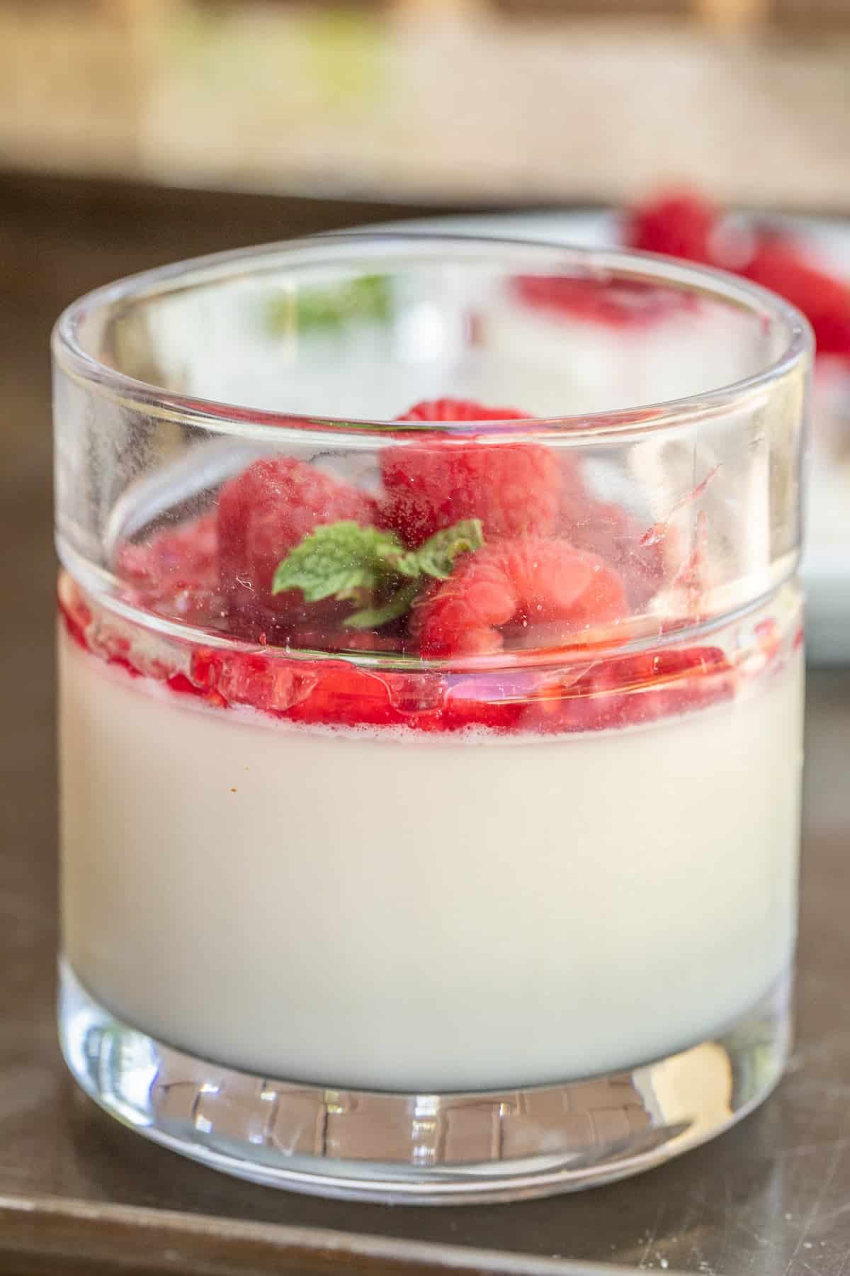 Classic Panna Cotta Dessert - An Easy No-Bake Dessert A glass dish with homemade panna cotta topped with raspberry jam.