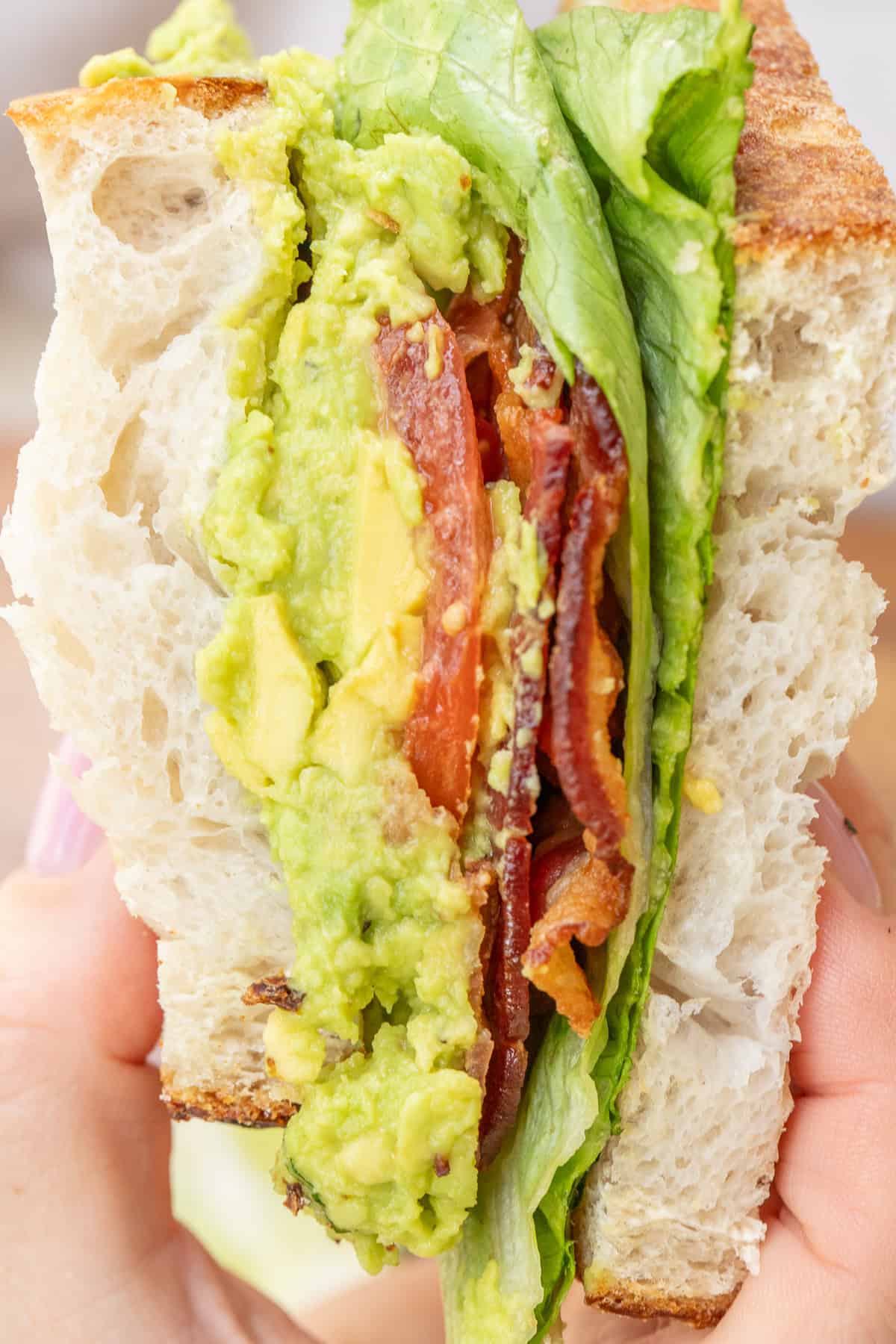 This BLT sandwich combines crispy bacon, ripe tomatoes, and crunchy lettuce in every bite. A sliced blt with layers of chunky avocado spread, crispy bacon, and juicy tomato slices.