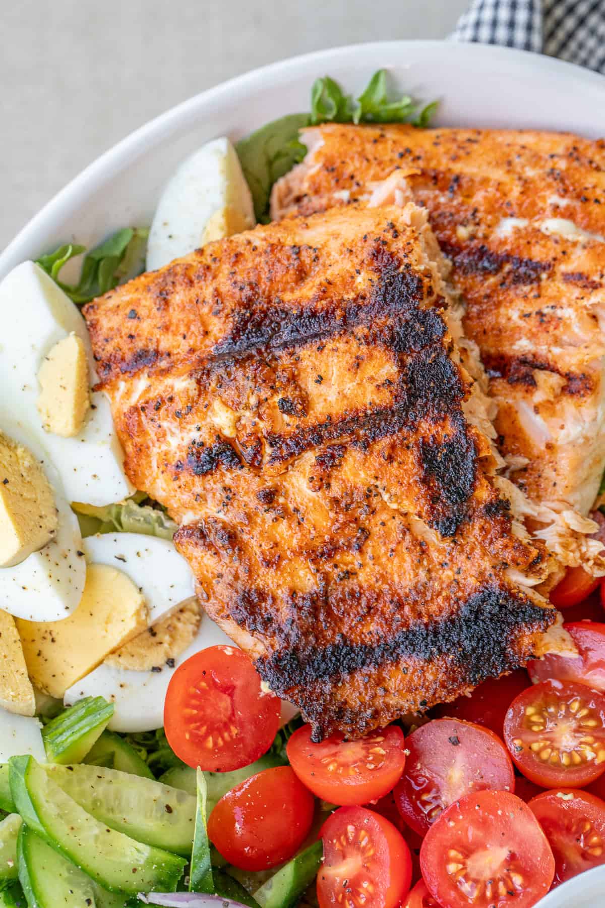 Learn how to make the best grilled salmon salad with perfectly seasoned salmon, avocado, and crisp greens. A bowl with the salmon salad and fresh toppings.