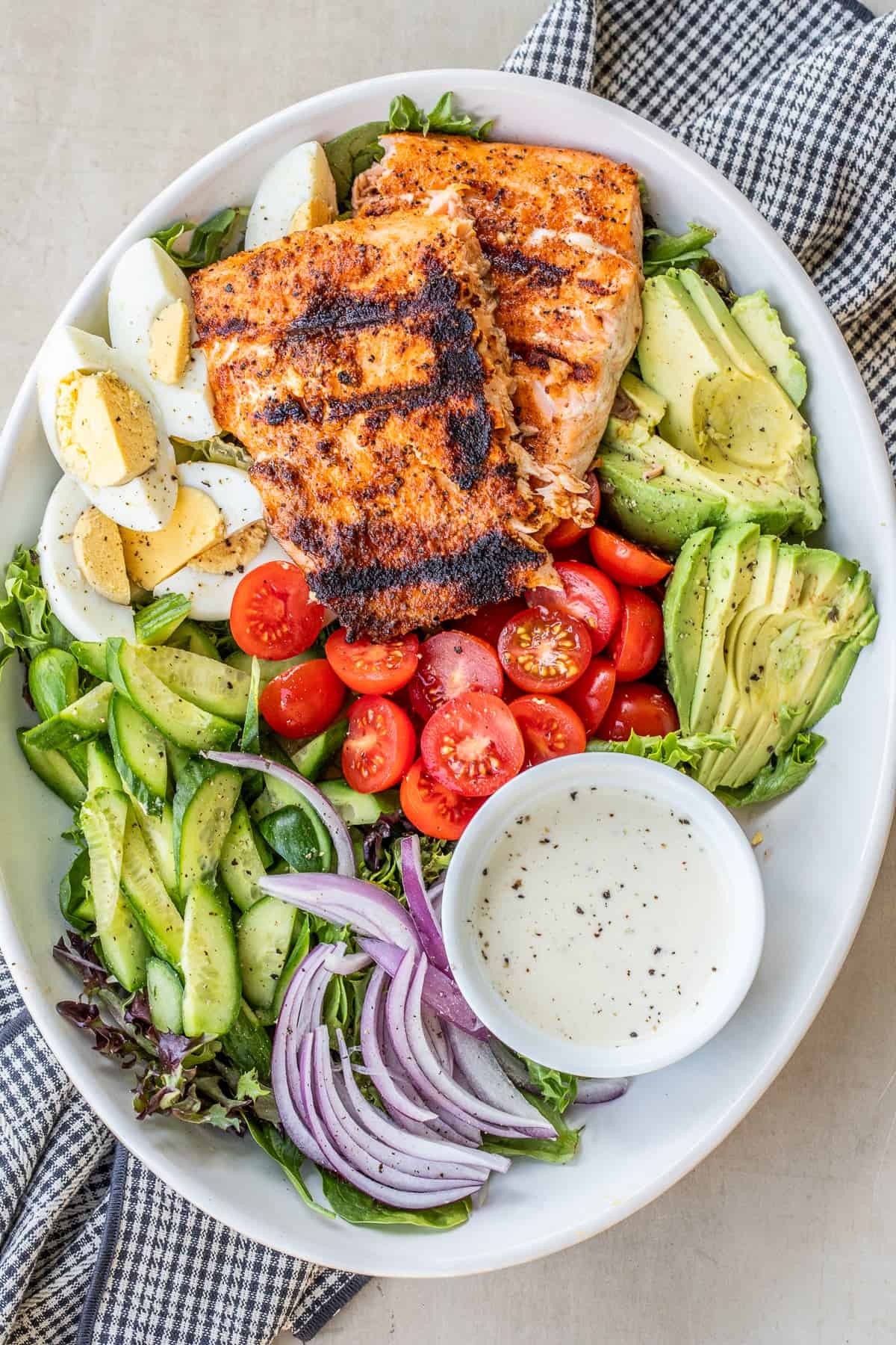 This grilled salmon salad is a healthy and protein-packed meal with fresh vegetables and homemade dressing. A large salad bowl with the grilled salmon salad.