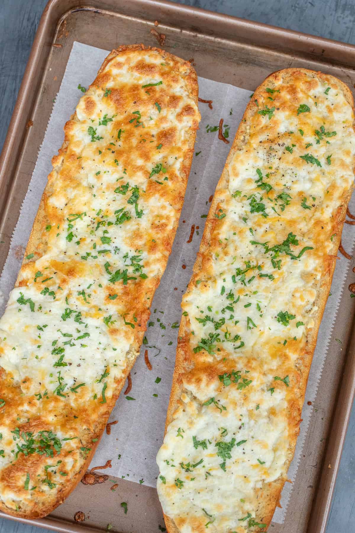 Easy Garlic Cheesy Bread Recipe A baking sheet with the baked cheesy loaves.