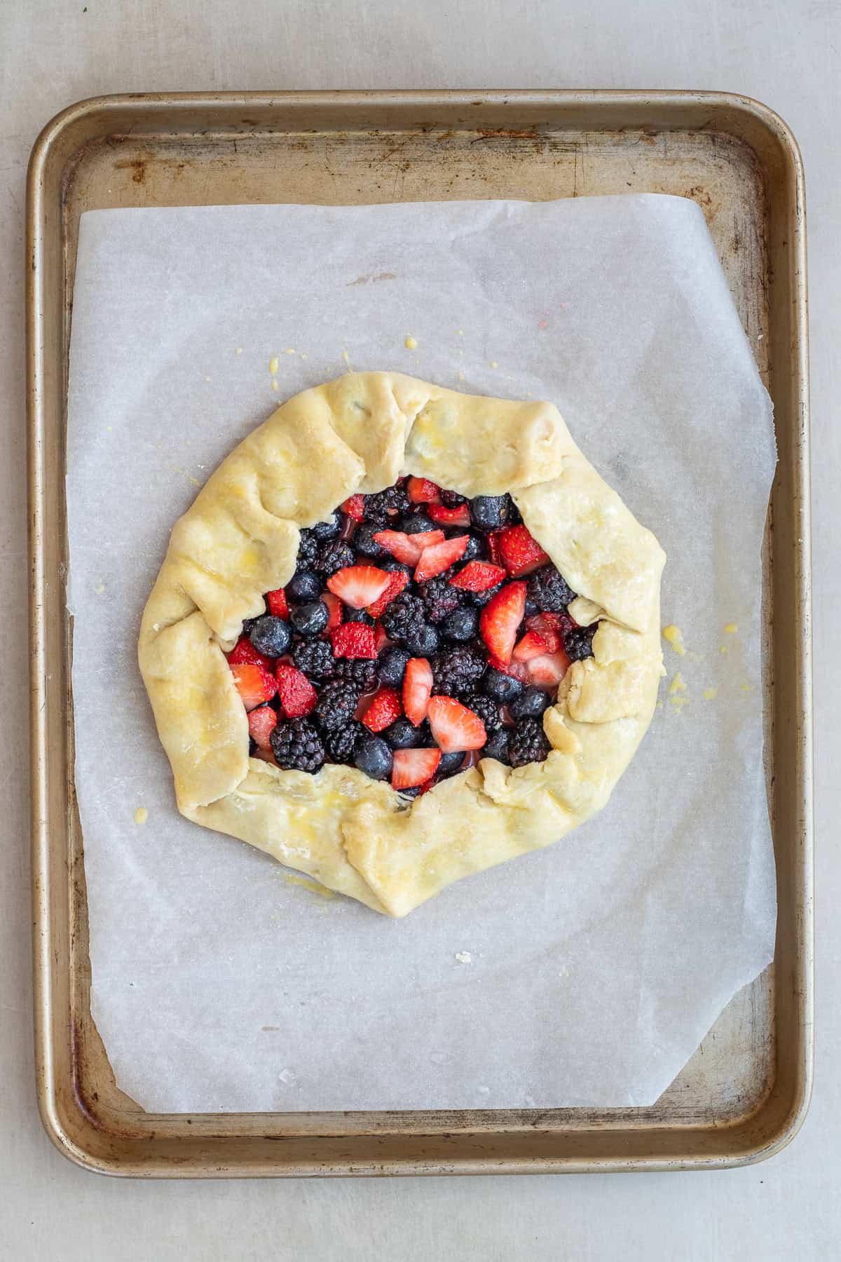 The Perfect Mixed Berry Galette with Sweet Juicy Berries The shaped berry galette on a sheet pan.