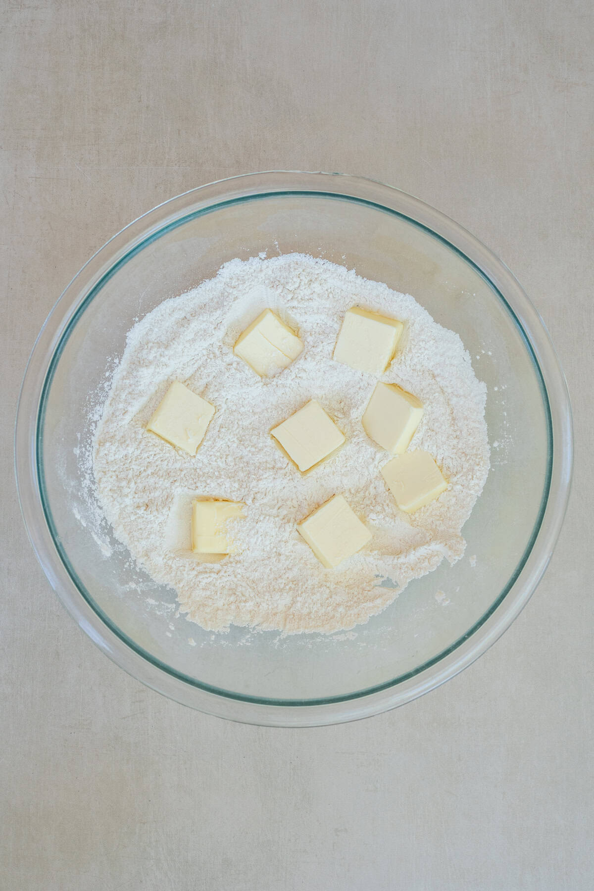 How to make homemade galette dough with a crisp, flaky texture and rich buttery flavor. A glass bowl with the dry ingredients and cubes of butter.