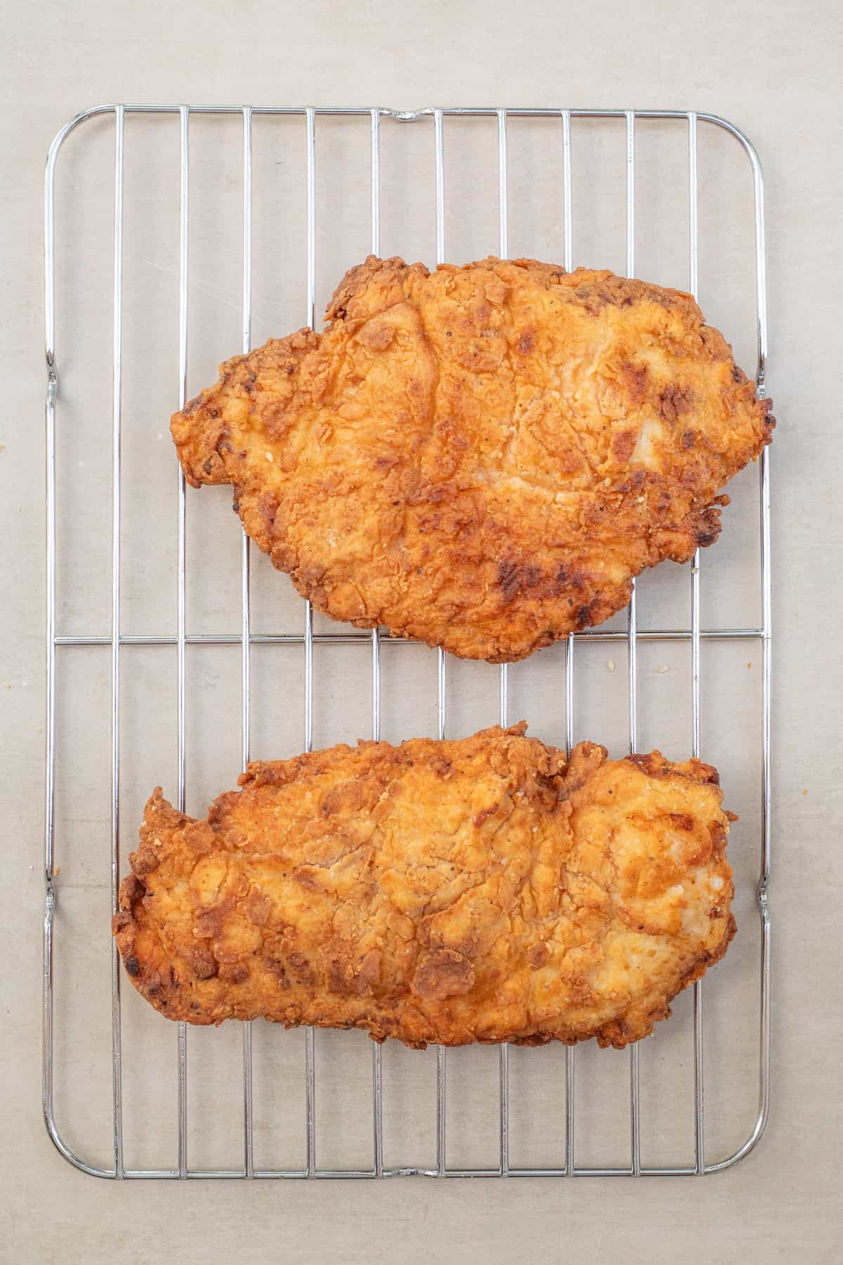 Buttermilk Fried Hot Honey Chicken Sandwich Fried chicken cutlets on a cooling wire rack.