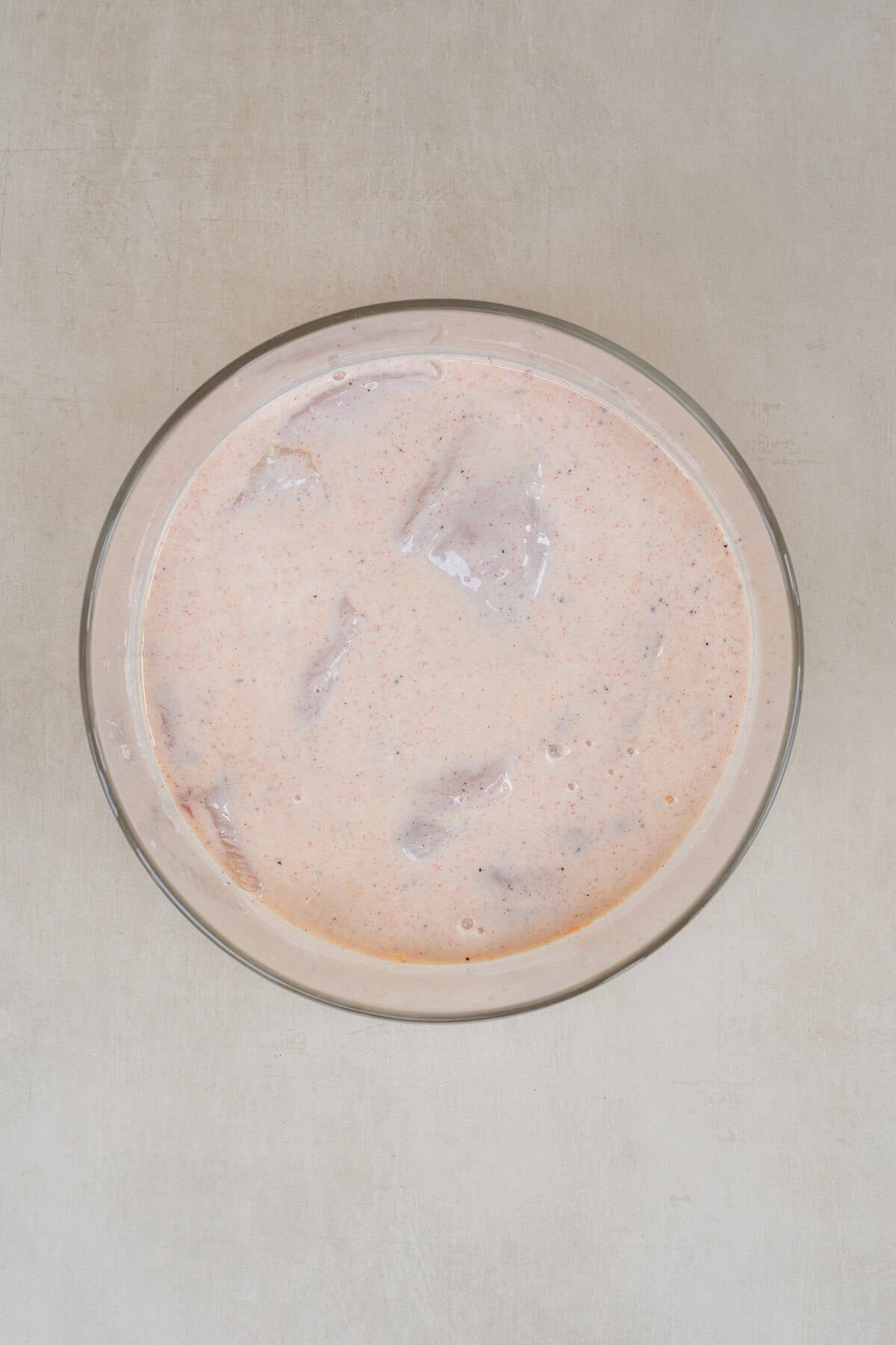Buttermilk Fried Hot Honey Chicken Sandwich A glass bowl with the buttermilk marinade.