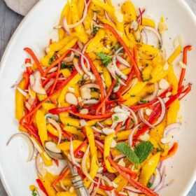A bowl of mango salad topped with almonds.