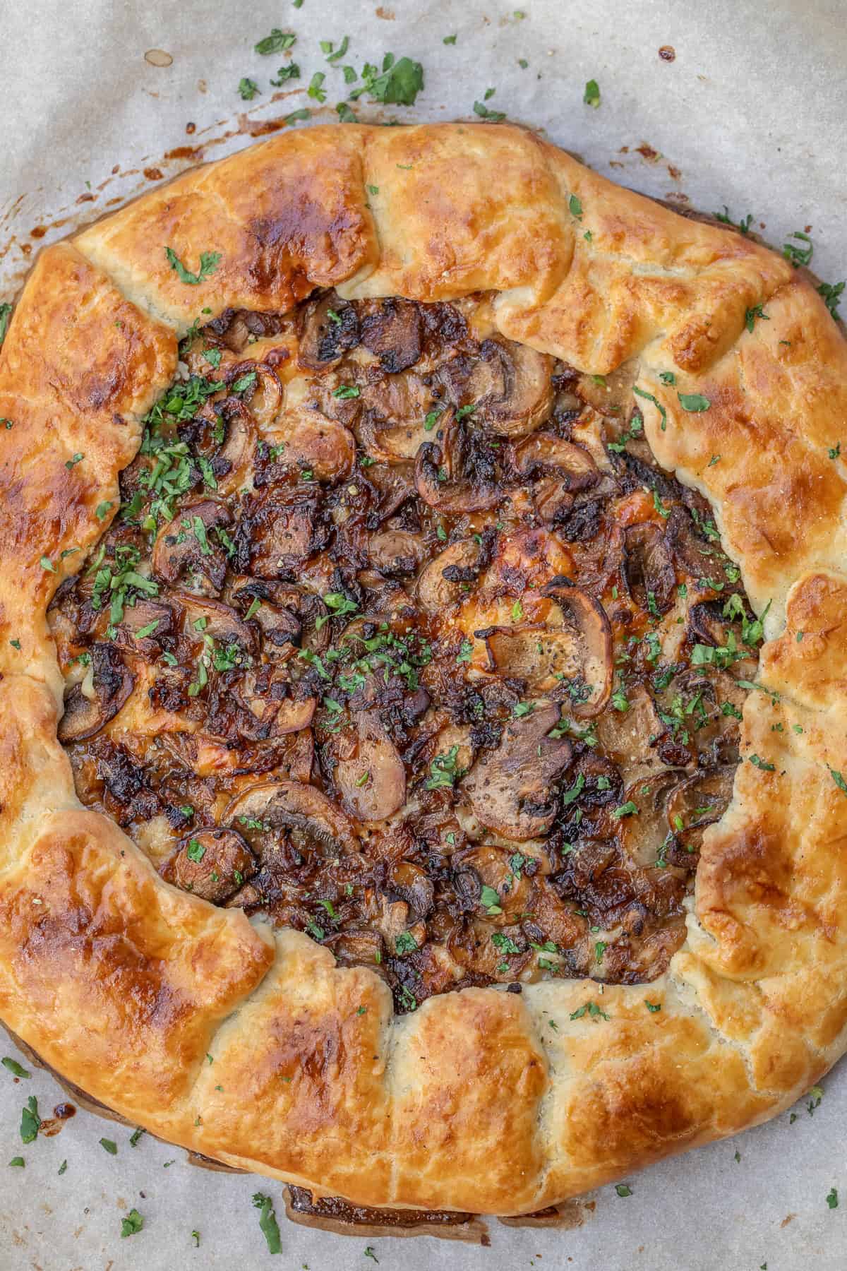 This homemade galette dough recipe creates a buttery, flaky crust perfect for sweet and savory galettes. A baked mushroom galette, topped with fresh herbs.