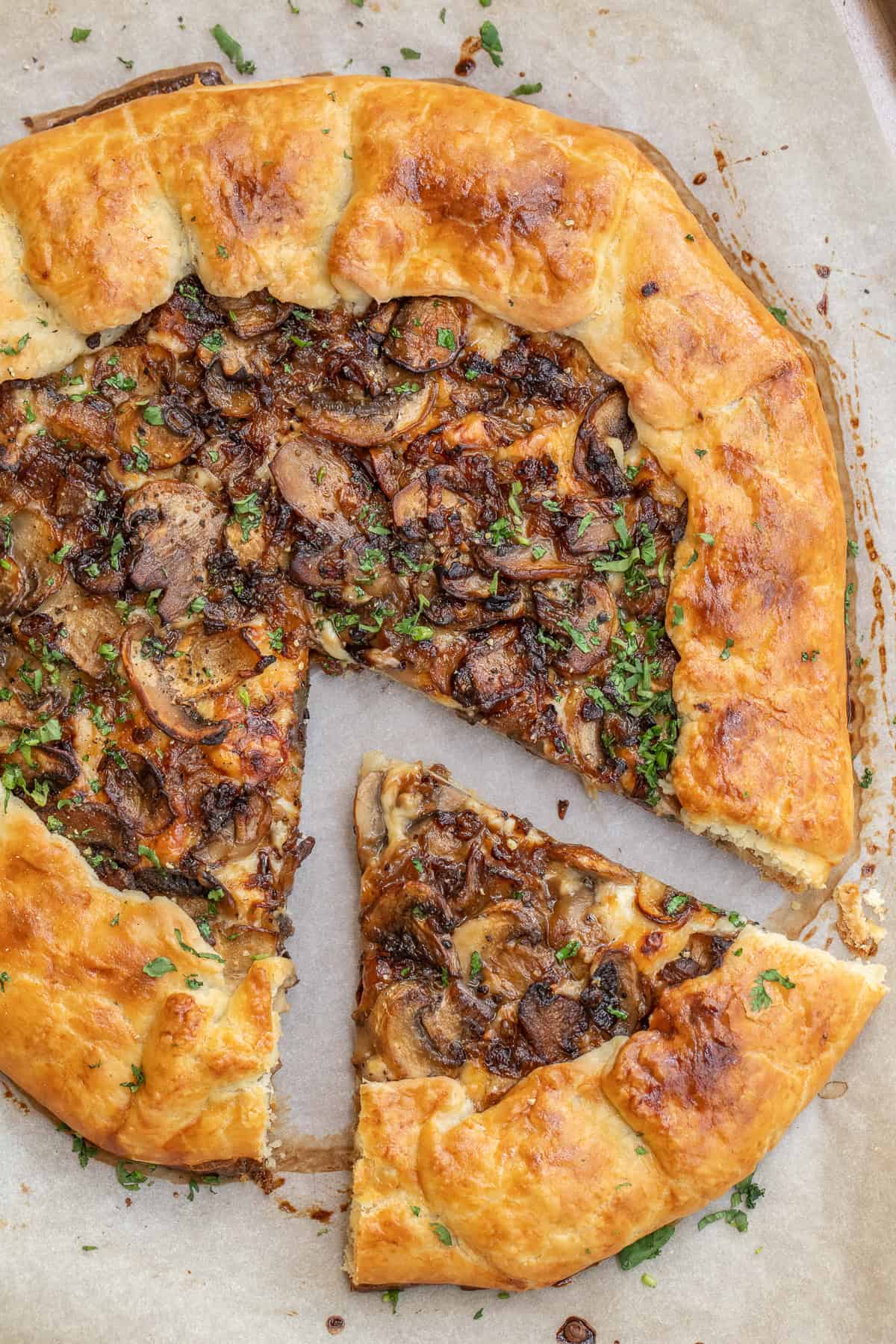 This savory mushroom galette is a simple vegetarian recipe with a crisp crust and rich mushroom flavor. A slice of a crispy and buttery mushroom galette.