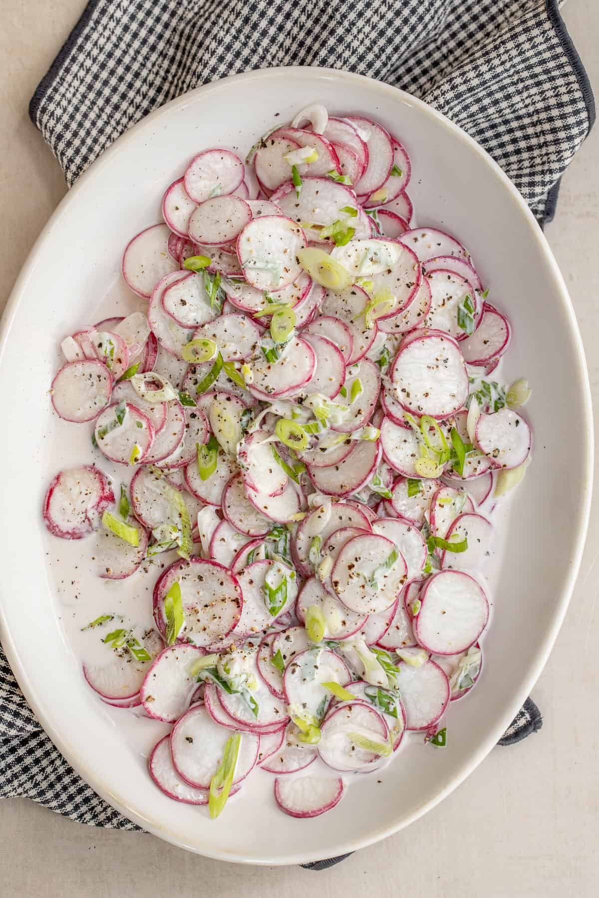 A fresh and crisp radish salad made with thinly sliced radishes. A large salad bowl with the creamy radish salad.
