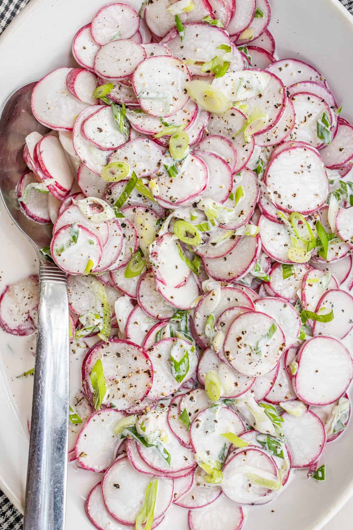 Fresh radishes are thinly sliced to make this simple salad. A sliced radish salad in a salad bowl.
