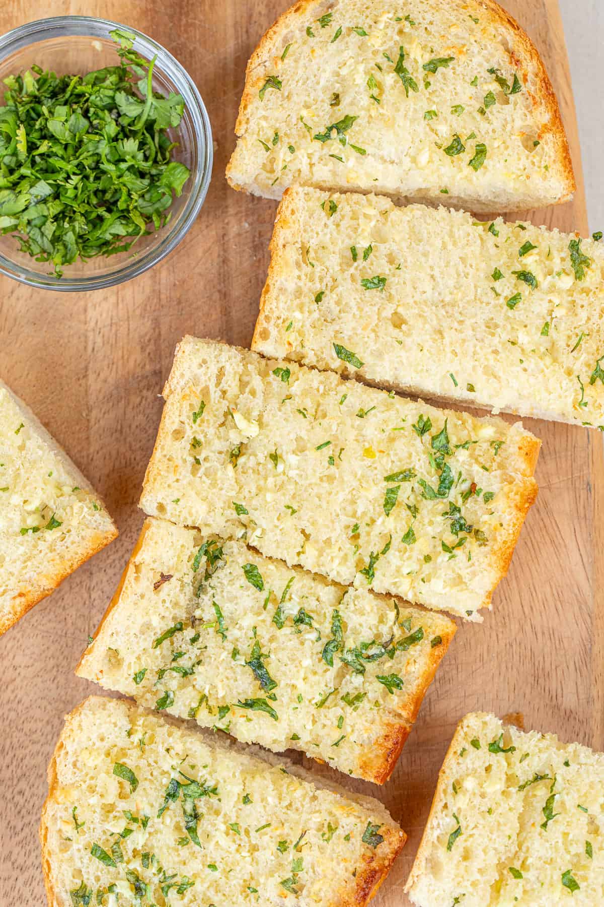 This homemade garlic bread is golden, buttery, and full of fresh garlic flavor. A sliced garlic bread loaf on a cutting board.