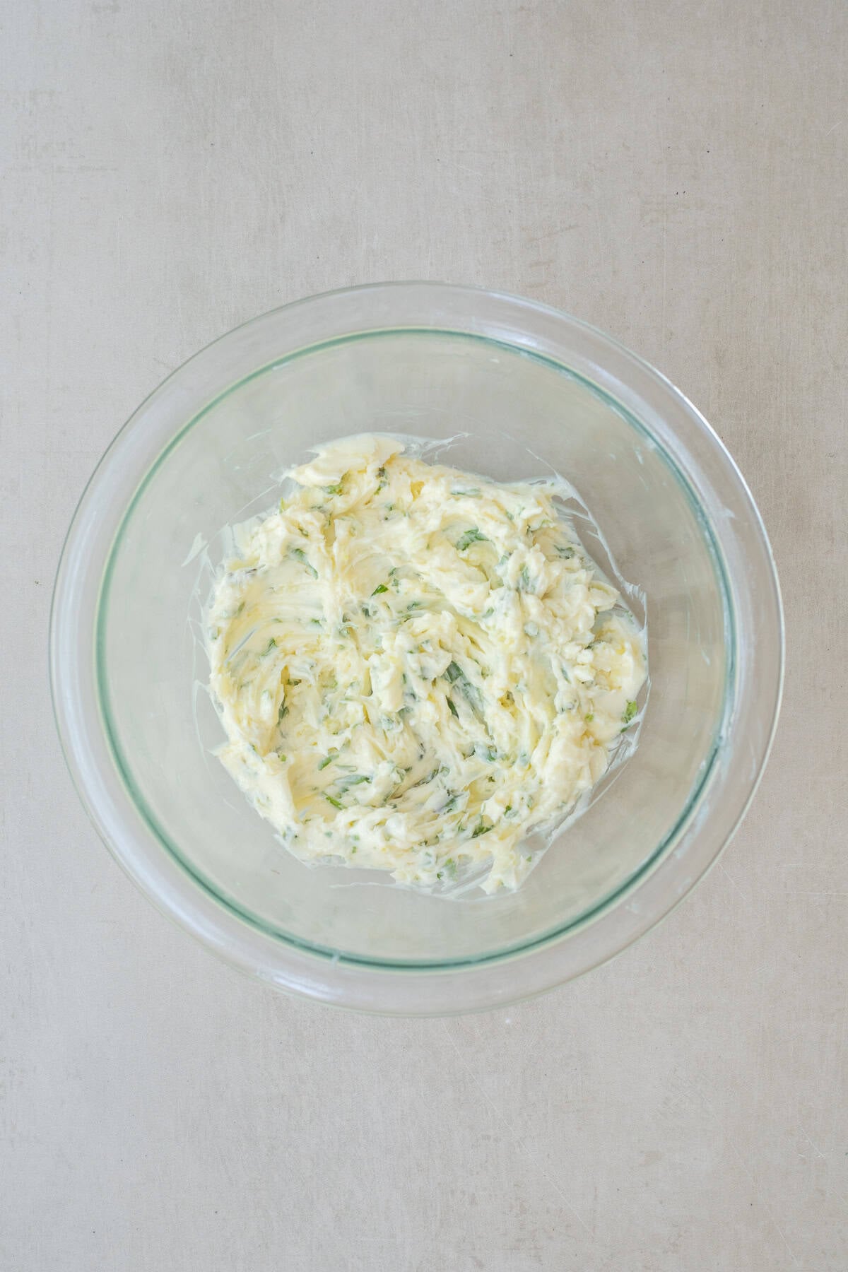 A loaf of French bread is transformed into delicious homemade garlic bread. A glass bowl with the garlic butter spread.