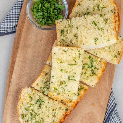 A cutting board with the slices of fresh garlic bread.