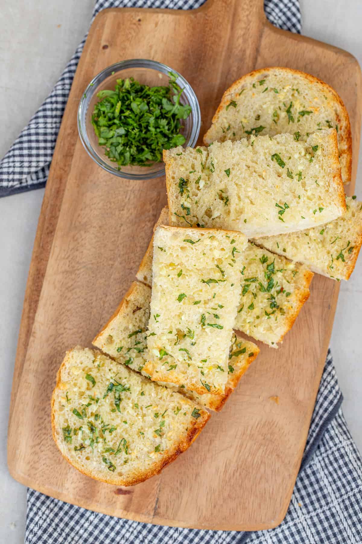 This easy garlic bread recipe comes together with a simple homemade garlic butter. A cutting board with the slices of fresh garlic bread.