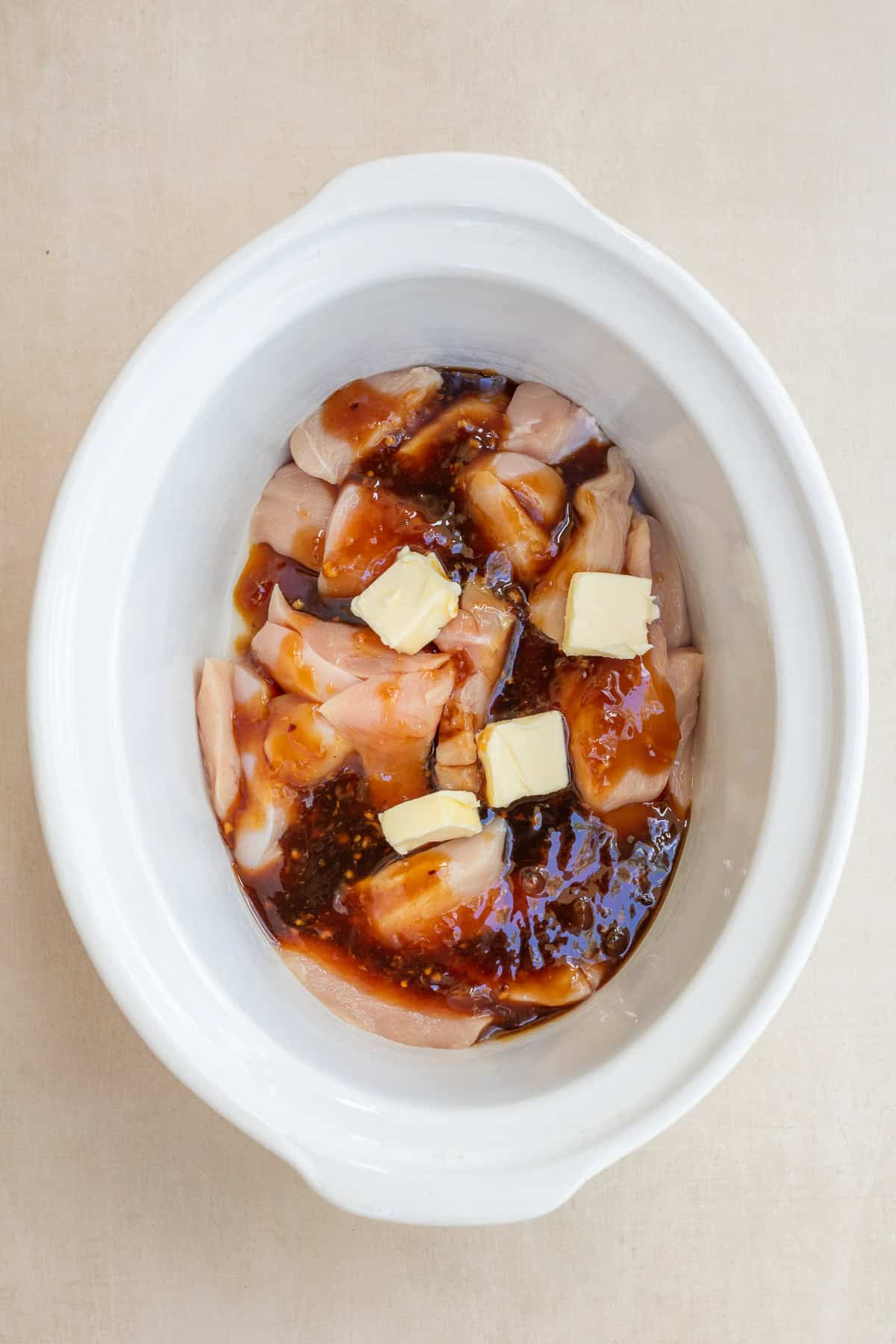 Homemade crockpot teriyaki chicken with tender pieces of chicken, broccoli, and a rich teriyaki sauce. A crockpot with the chicken breast, butter, and teriyaki sauce.