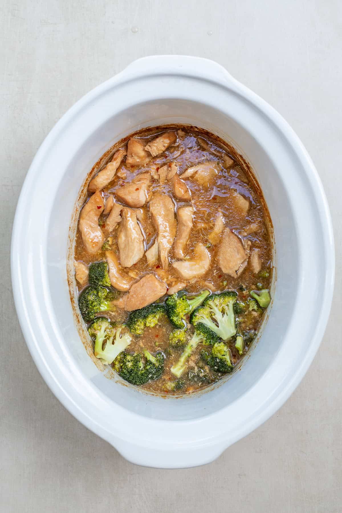 Sweet and savory crockpot teriyaki chicken made with tender chicken, broccoli, garlic, and ginger. The cooked chicken and broccoli in a slow cooker.