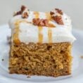 A pumpkin sheet cake, topped with pumpkin frosting, nuts, and a caramel drizzle.