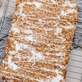 A pumpkin coffee cake on a wire rack topped with glaze.
