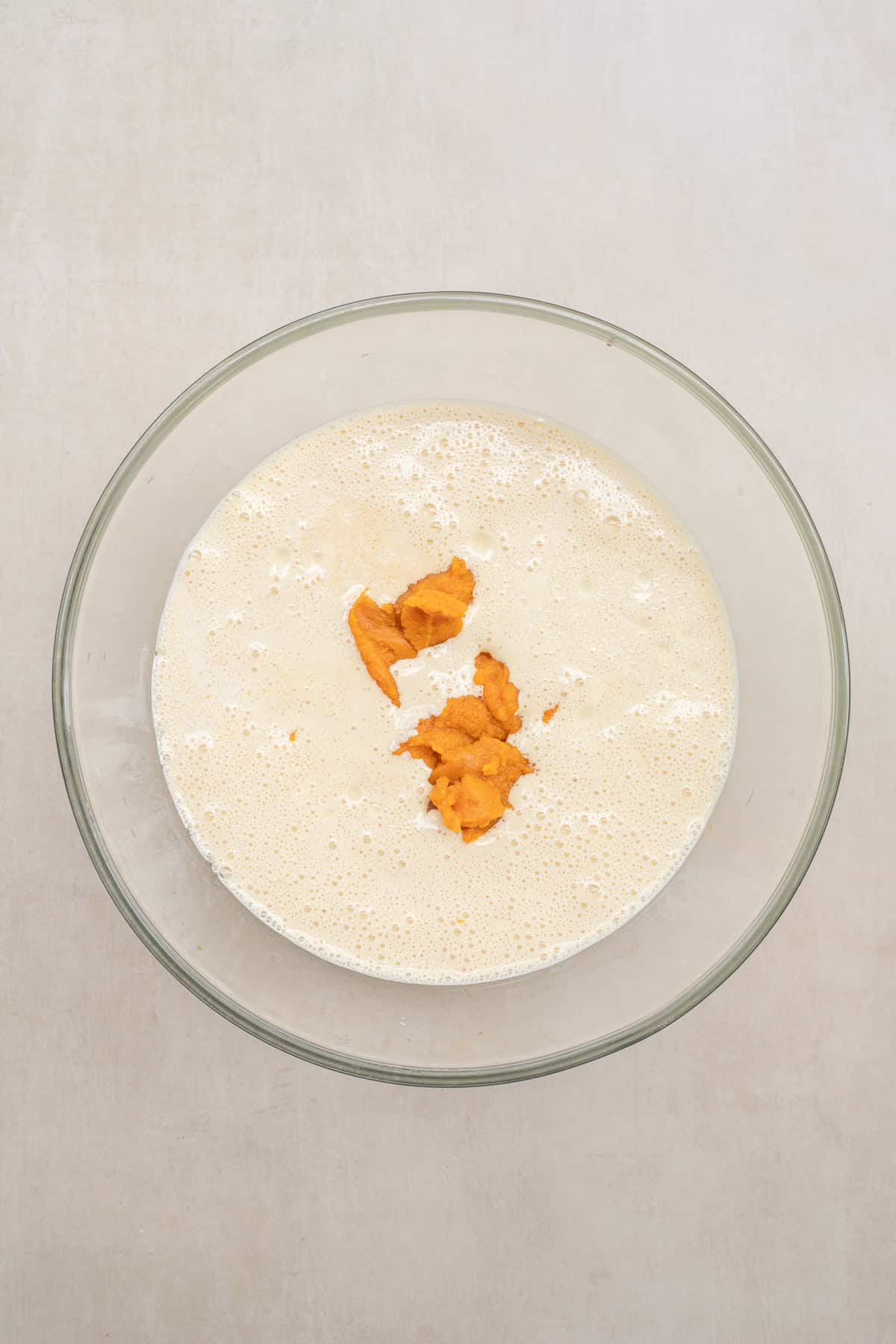 A classic pumpkin coffee cake made with pumpkin puree and warm fall spices, finished with a sweet glaze. A glass bowl with the wet batter and pumpkin puree.