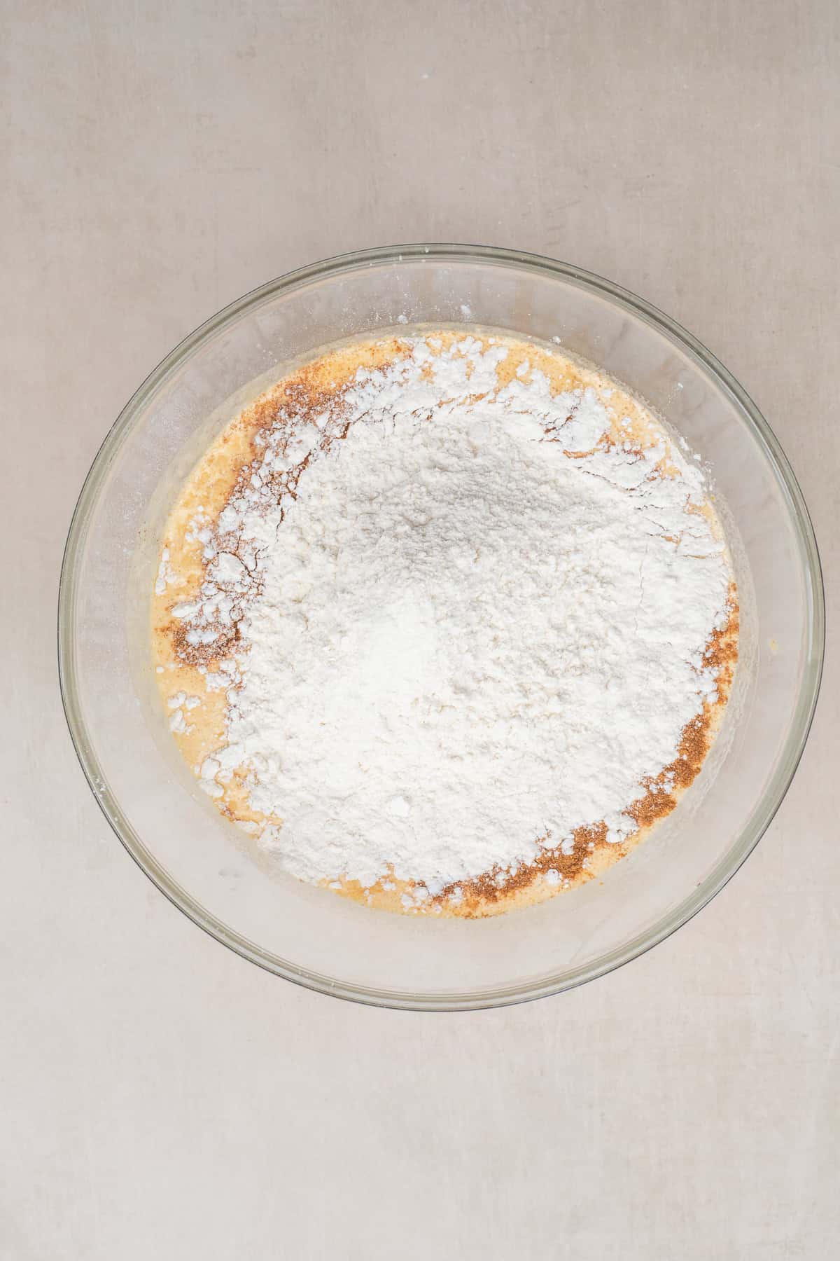 Moist pumpkin coffee cake with a tender crumb, buttery streusel topping, and simple vanilla glaze. A glass bowl with the wet batter topped with the dry ingredients.